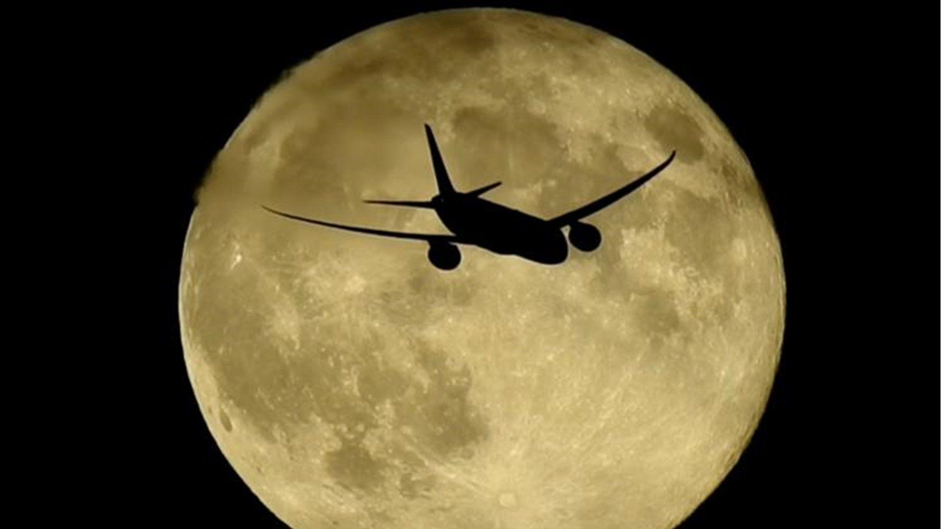 Yellow hue to full moon with the silhouette of an aeroplane crossing in front 