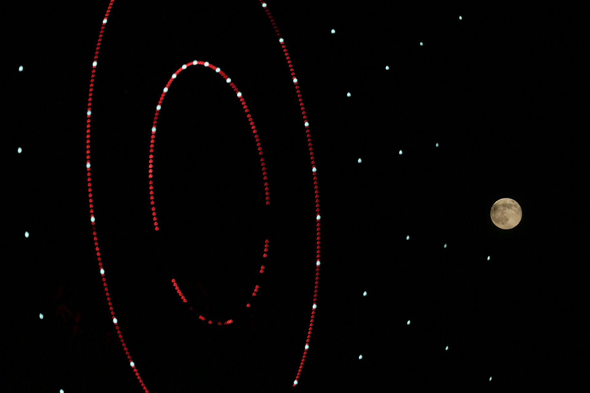 Abstract lights of a turning wheel are pictured against a dark night sky with the Moon on the right in Idlib on Wednesday.