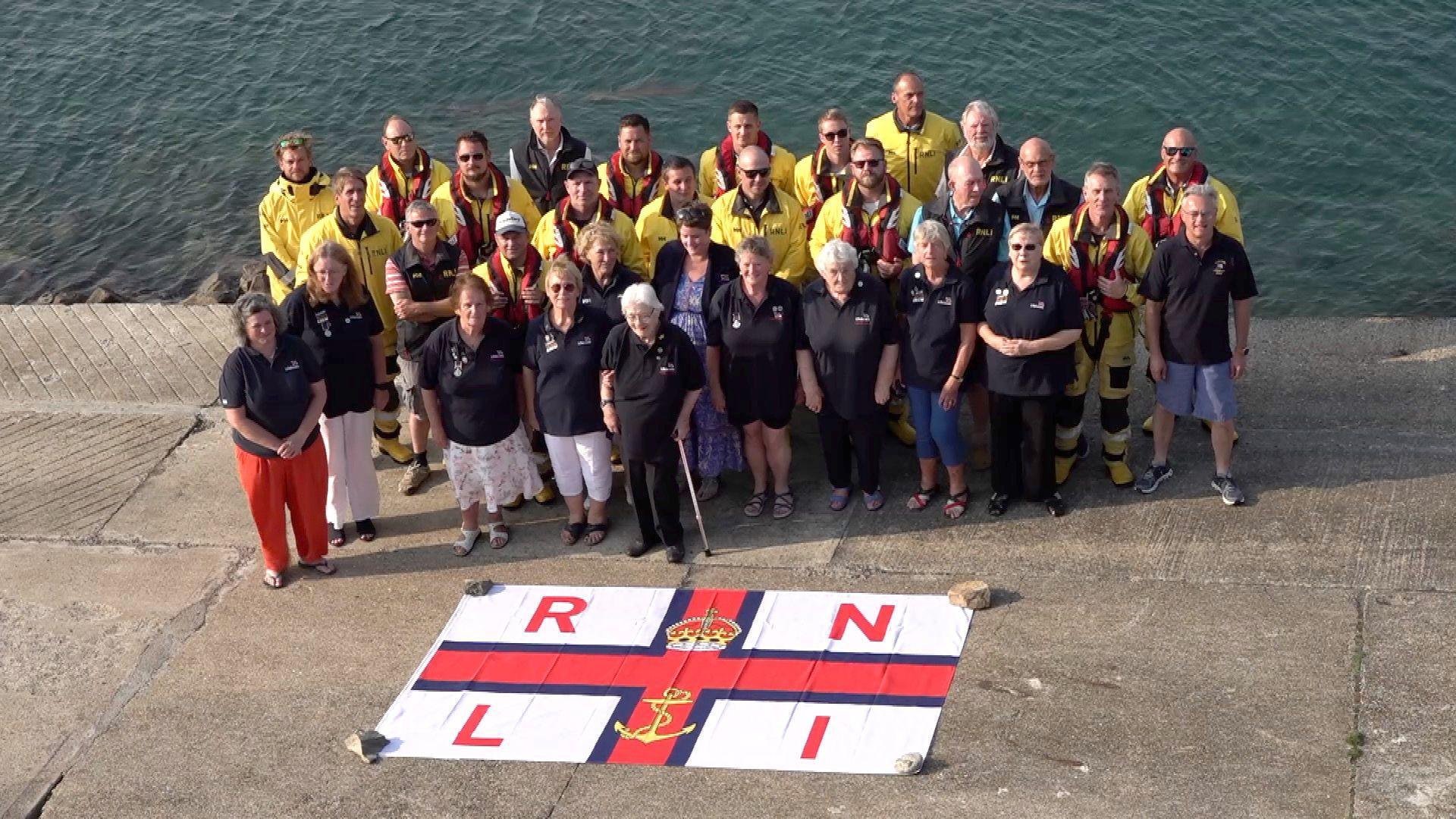 RNLI member by a quayside with the charity's flag on the ground in front of them