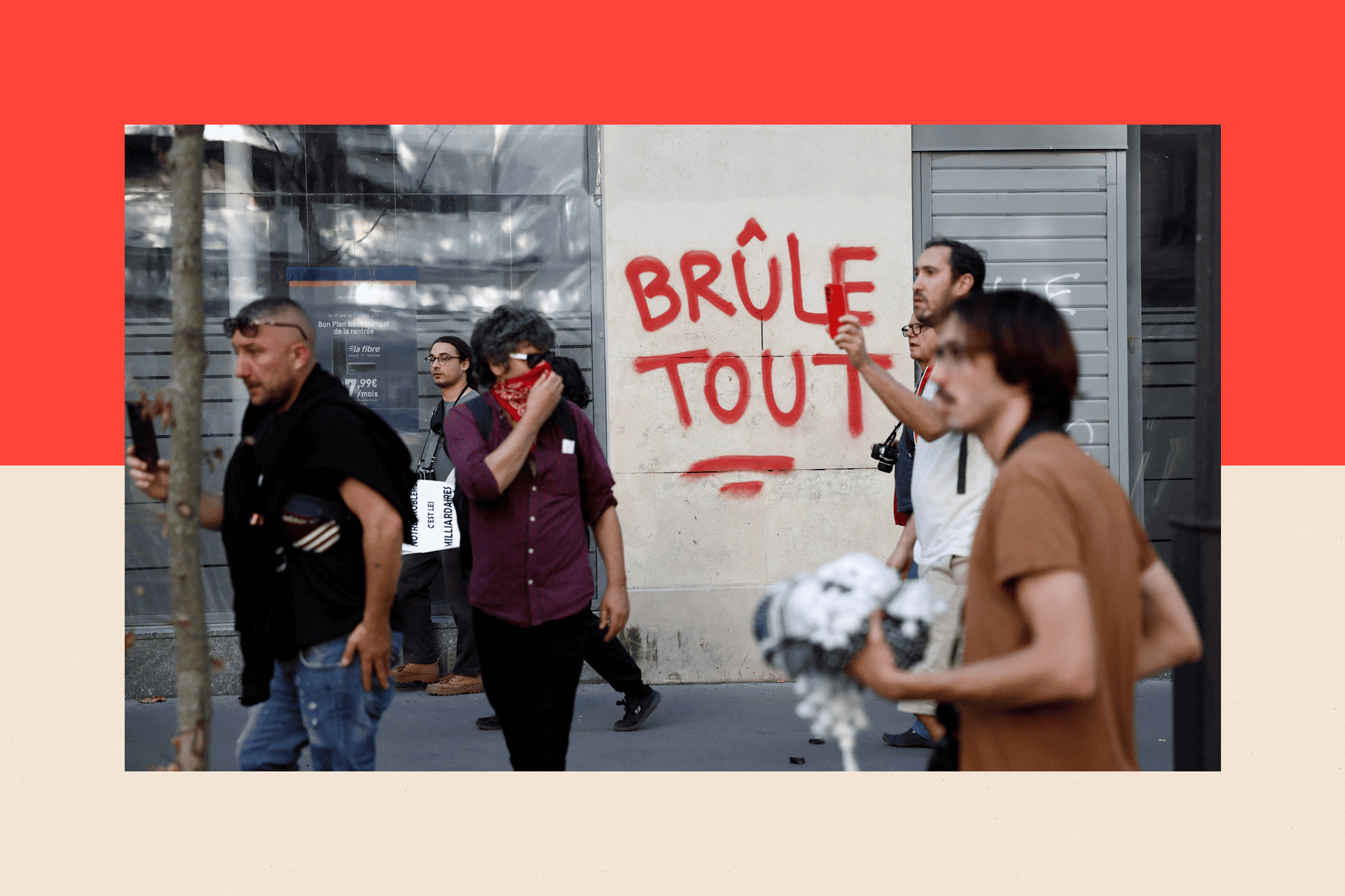 Protesters walk past the slogan "Burns everything" paint on a wall 