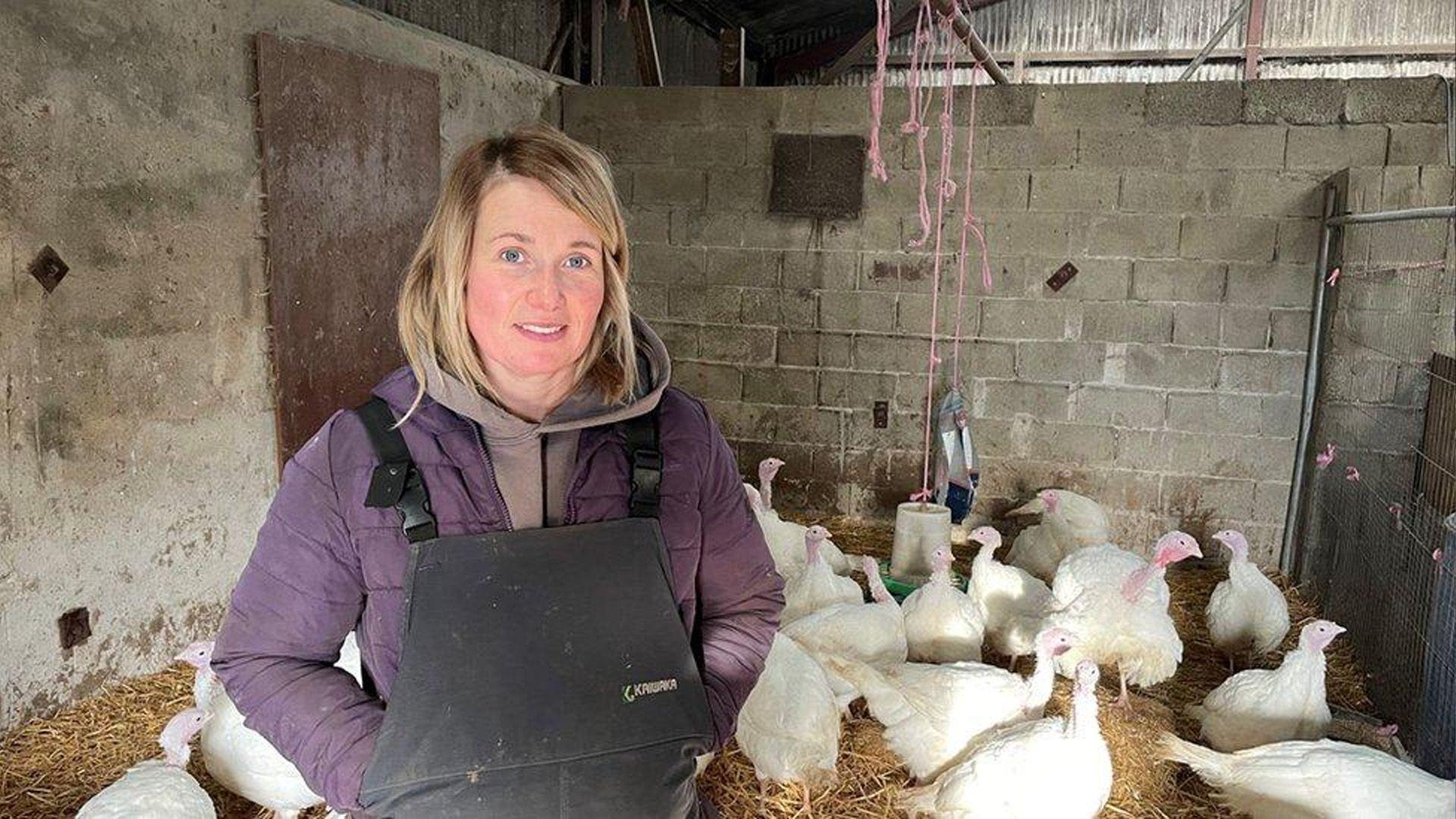 Gwenno Pugh, ffermwraig, yn sefyll o flaen tyrcwn