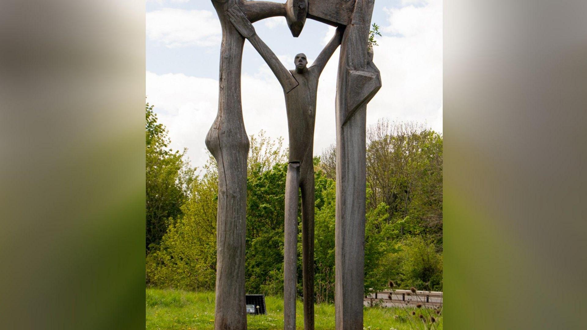 the Peterborough Arch sculpture of a wooden man standing under a wooden arch