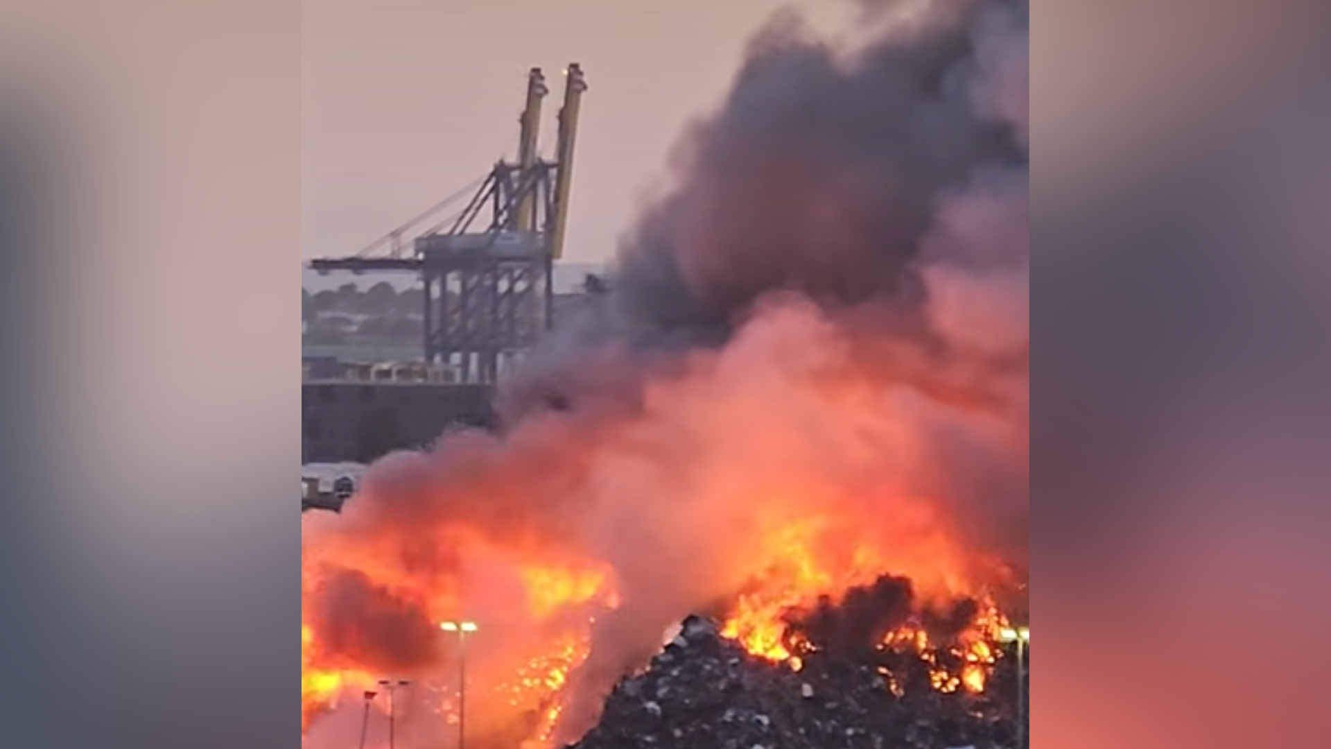 A fire in a scrap metal stack. Fire and smoke is billowing from the stack of scrap metal.