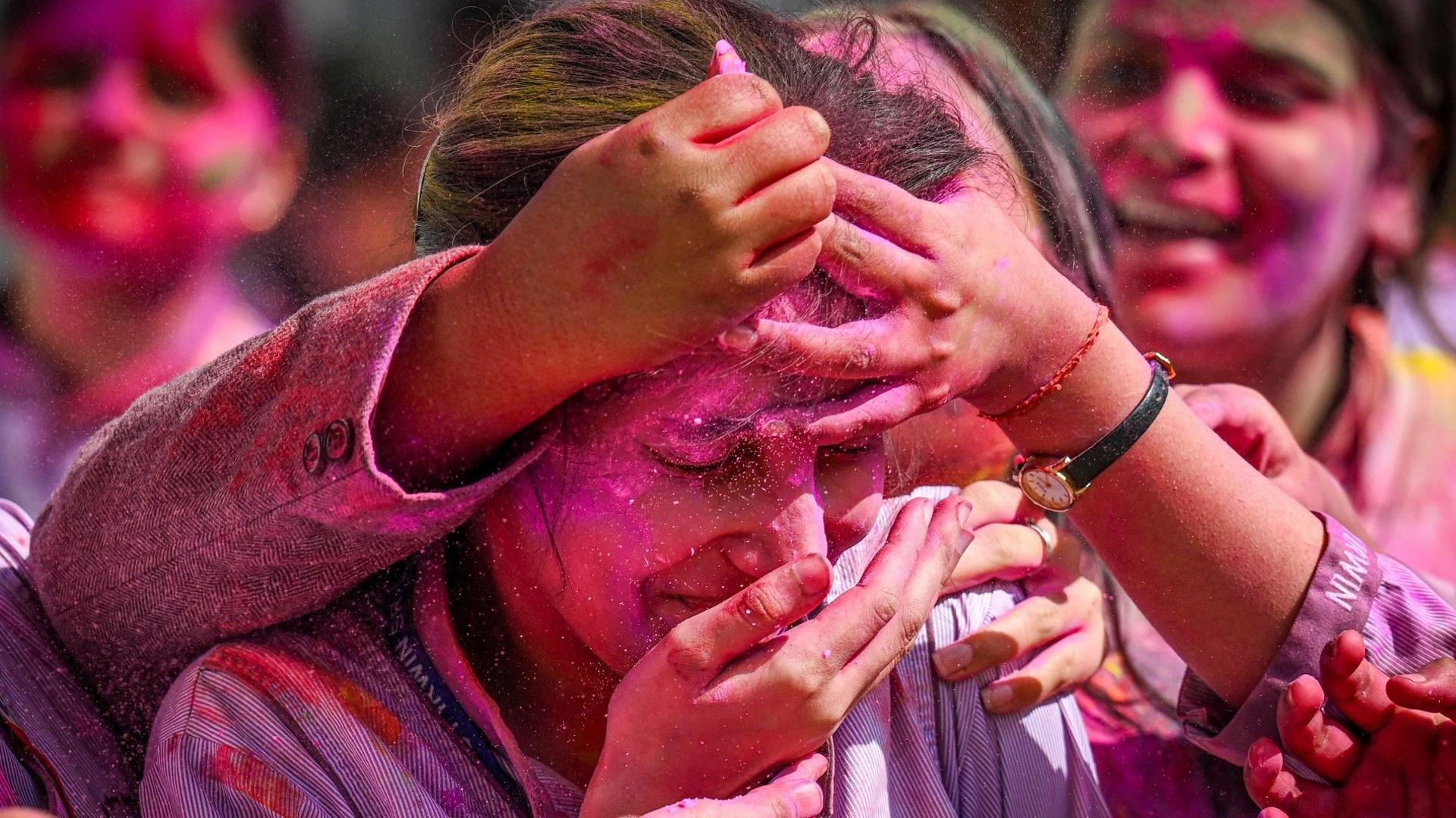 Young women seen smearing colour on a friend's face