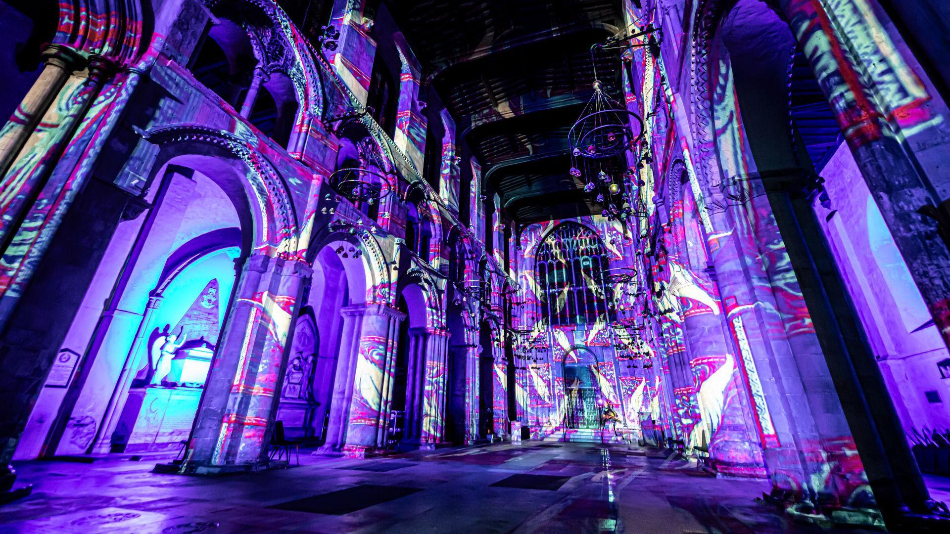 The inside of a church is lit with vibrant purple lighting. 