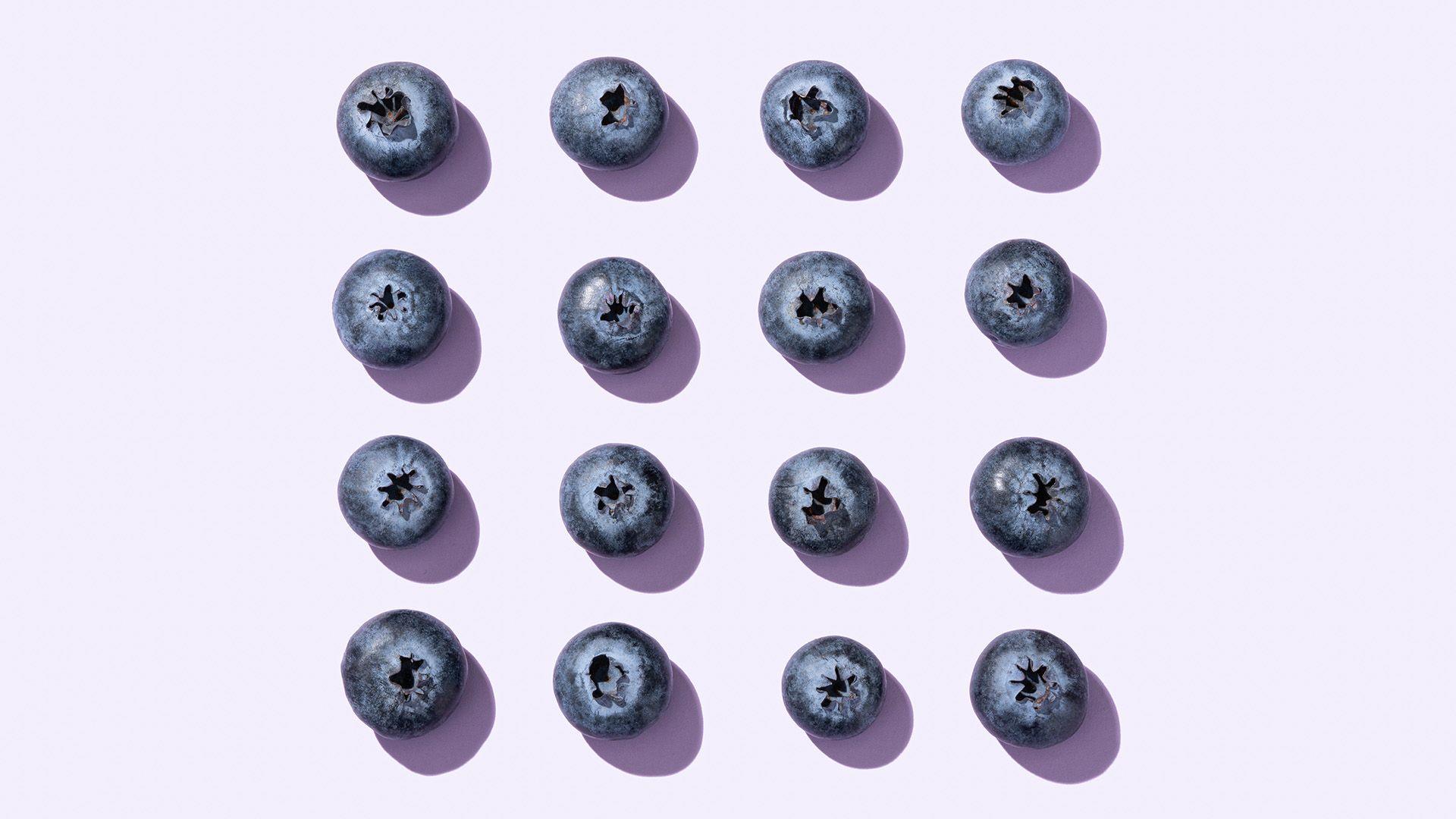 Blueberries arranged in a square on a light purple background