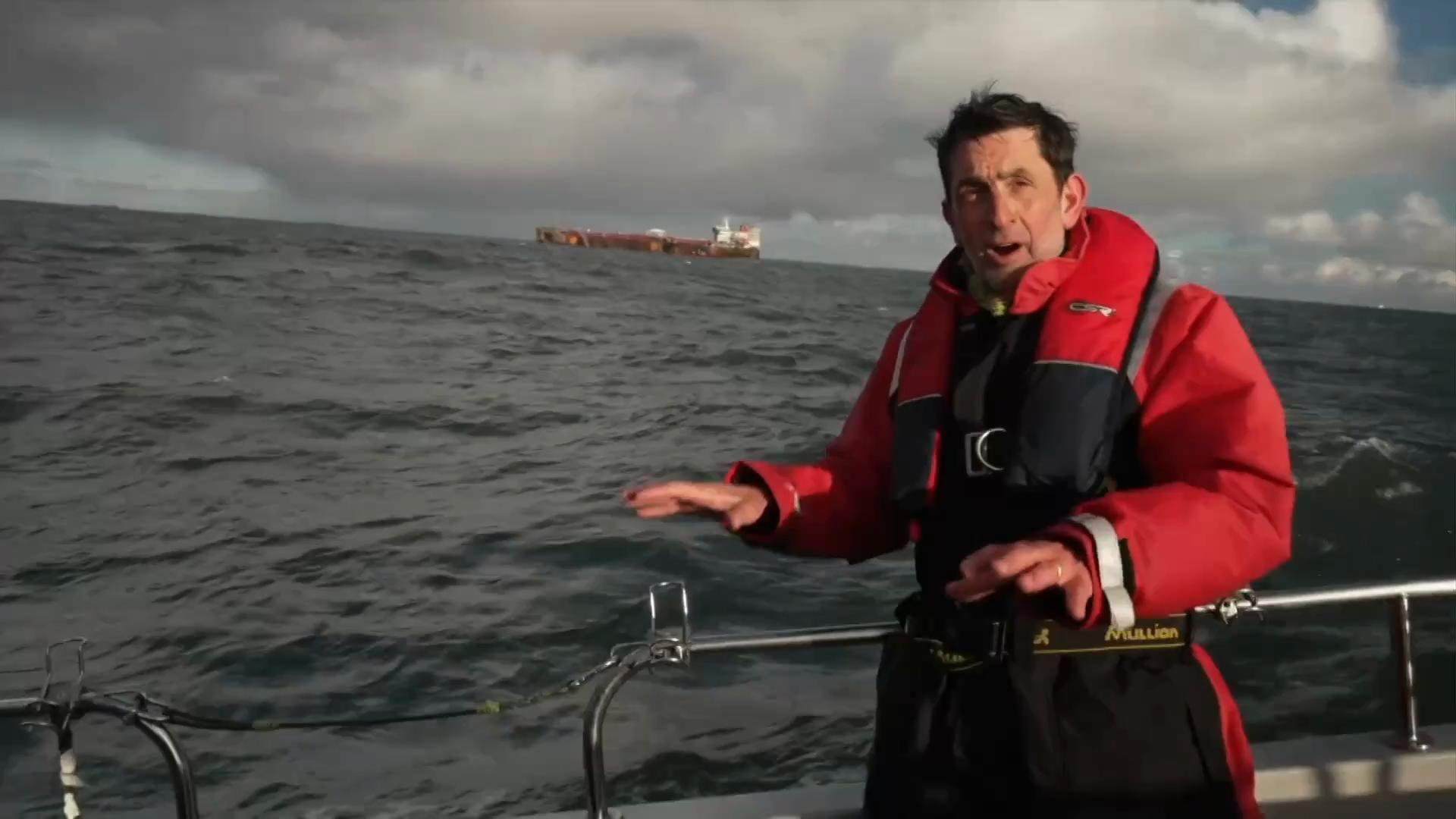 Justin Rowlatt on a boat wearing a red jacket