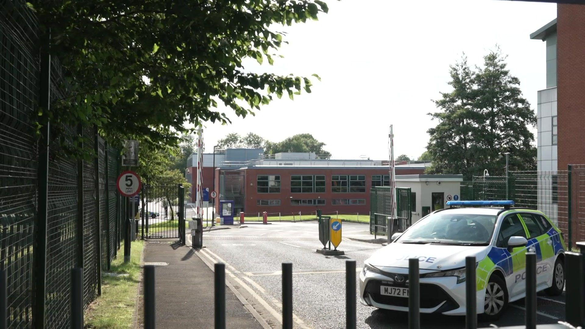 A police car is behind black bollards close to the car park where a 19-year-old was killed.