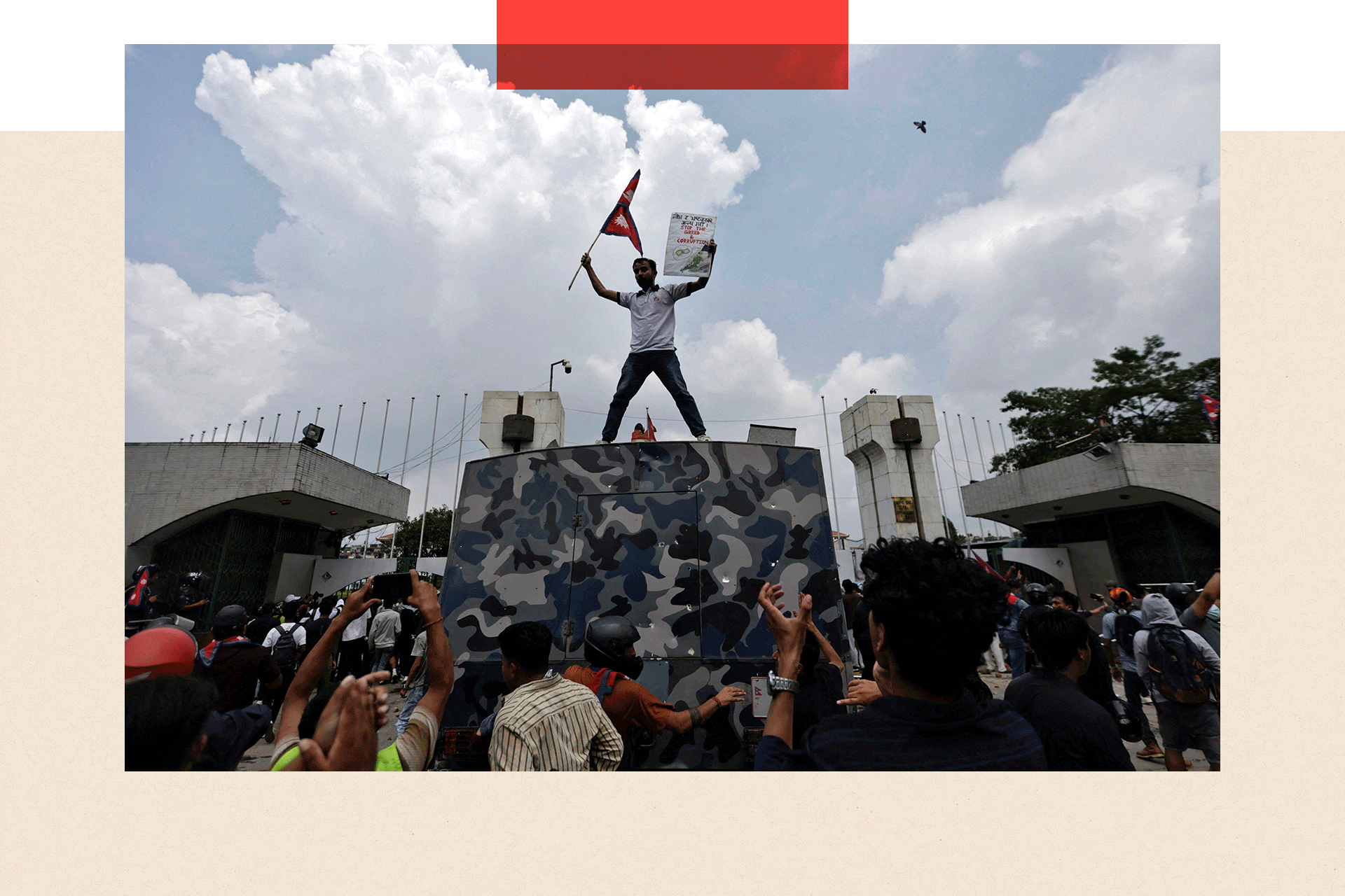 A demonstrator waves a flag as he stands atop a vehicle near the entrance of the Parliament