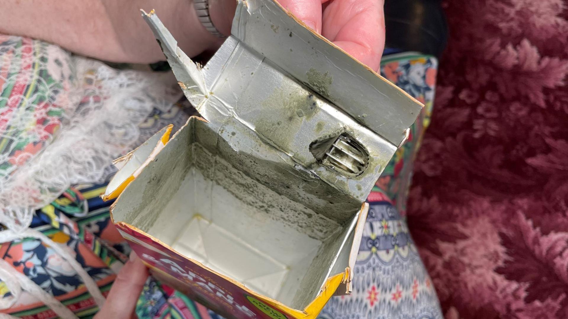 The inside of a juice carton which shows black marks.