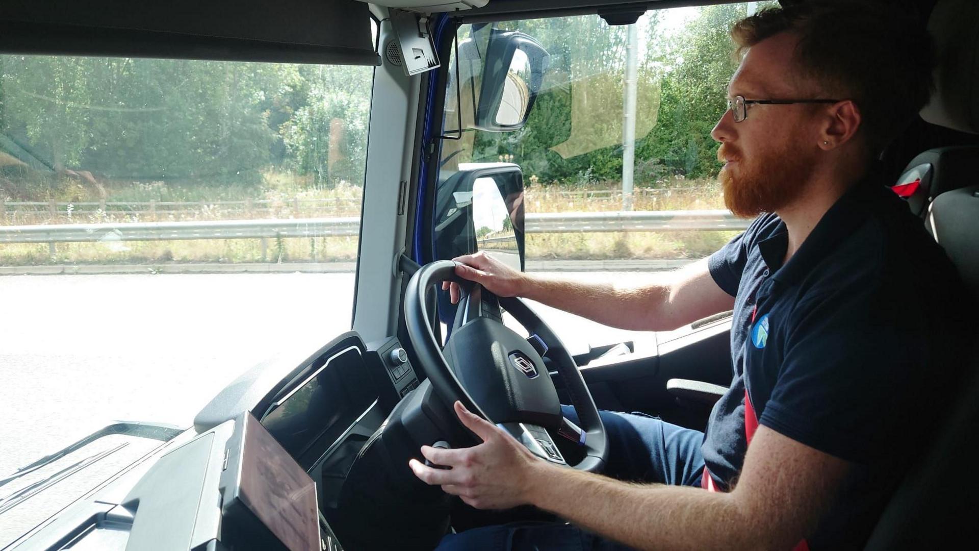 Lorry driver Liam Ely sitting at the wheel as he drives down a road