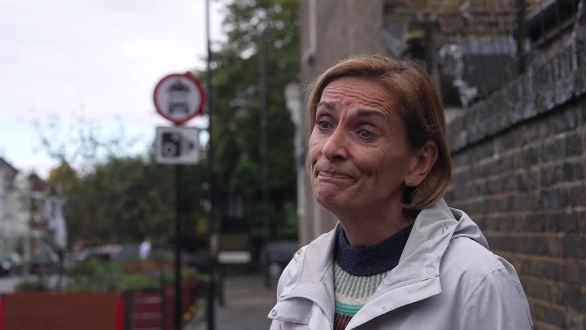 Jackie Dishman, a woman wearing a coat and jumper looks to the left of the camera with a wry expression.