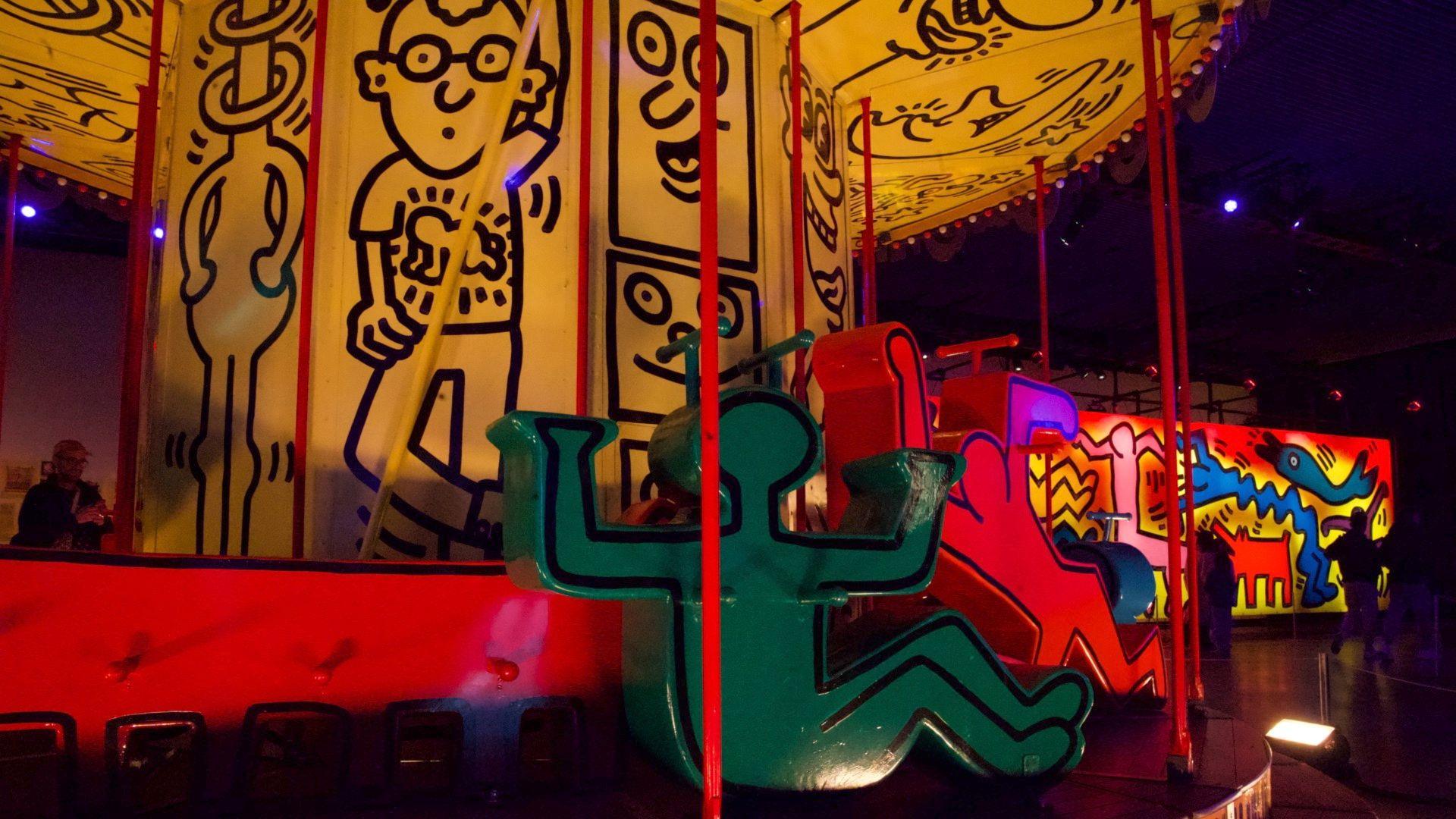 Keith Haring's carousel with bold cartoon figures is in close up.