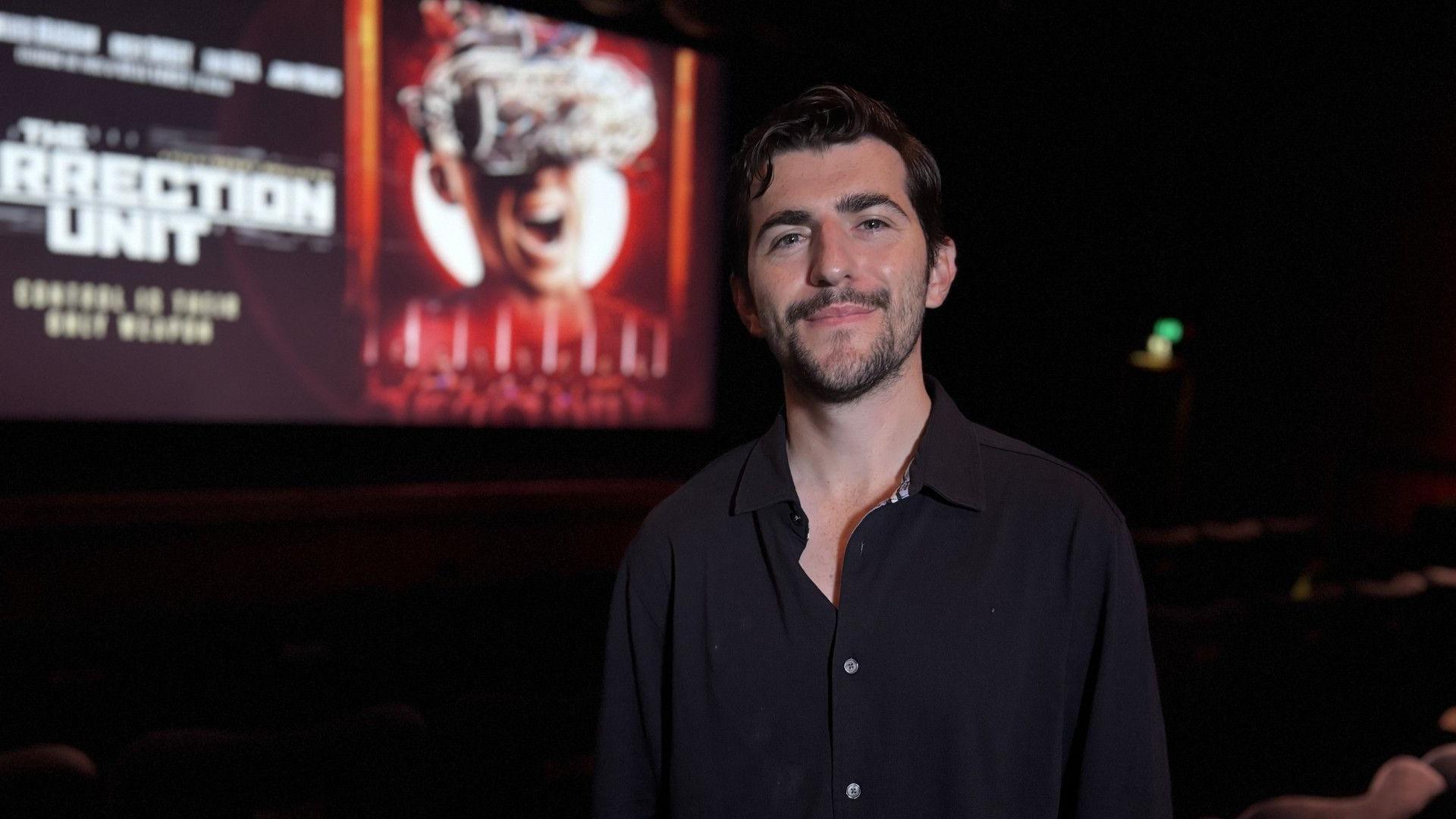 Film director, Derry Shillitto, stood in the auditorium of Broadway Cinema, Nottingham, with a projection of The Correction Unit film poster in the background.   