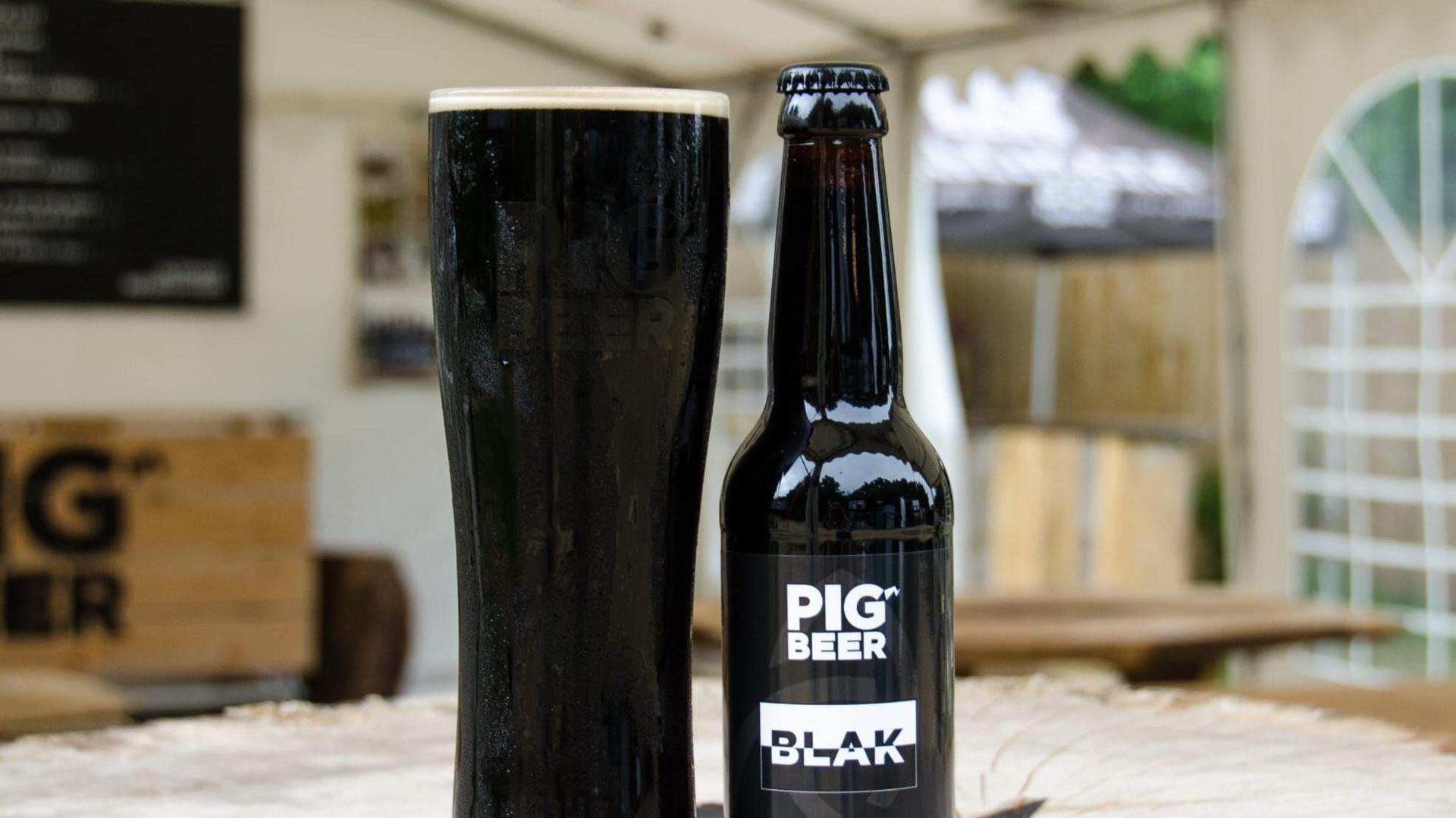 A black pint next to a black bottle.