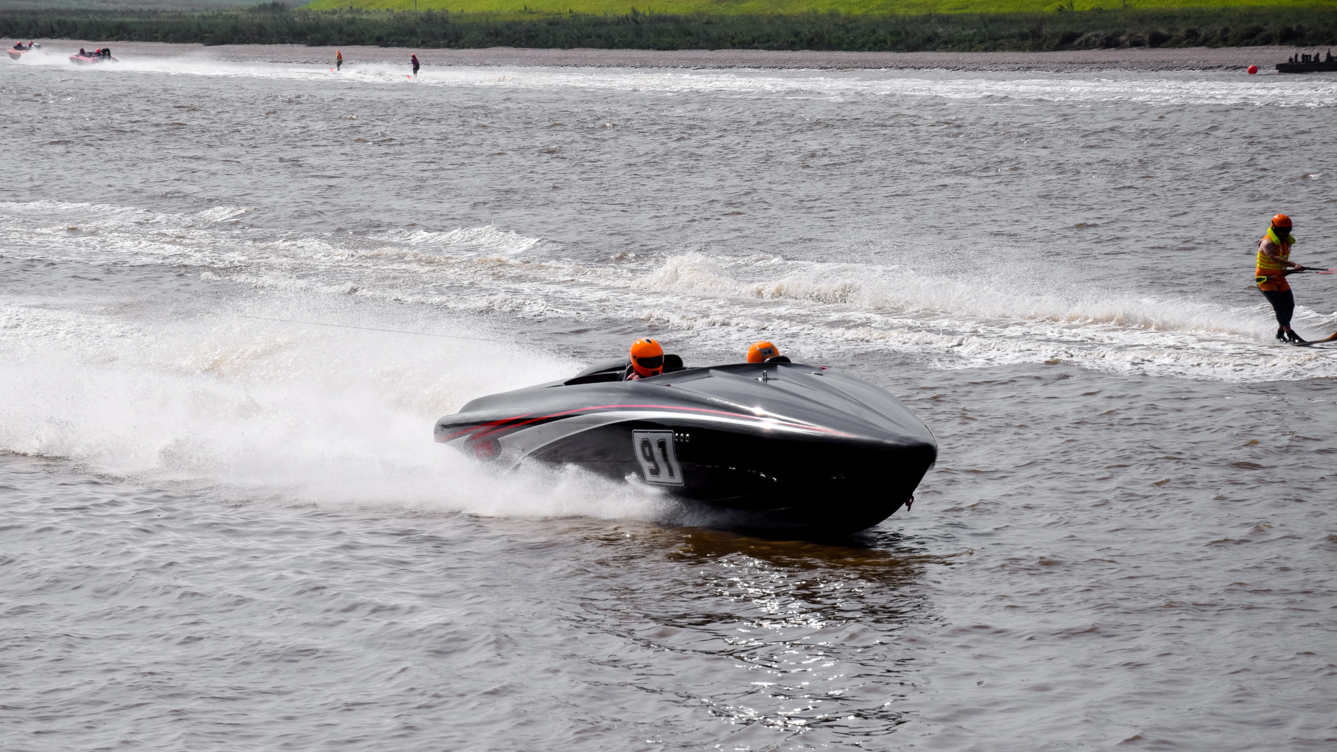 A power boat, travelling along the Great Ouse river. The driver is wearing a bright orange helmet. The number 91 is displayed on the side of the boat.