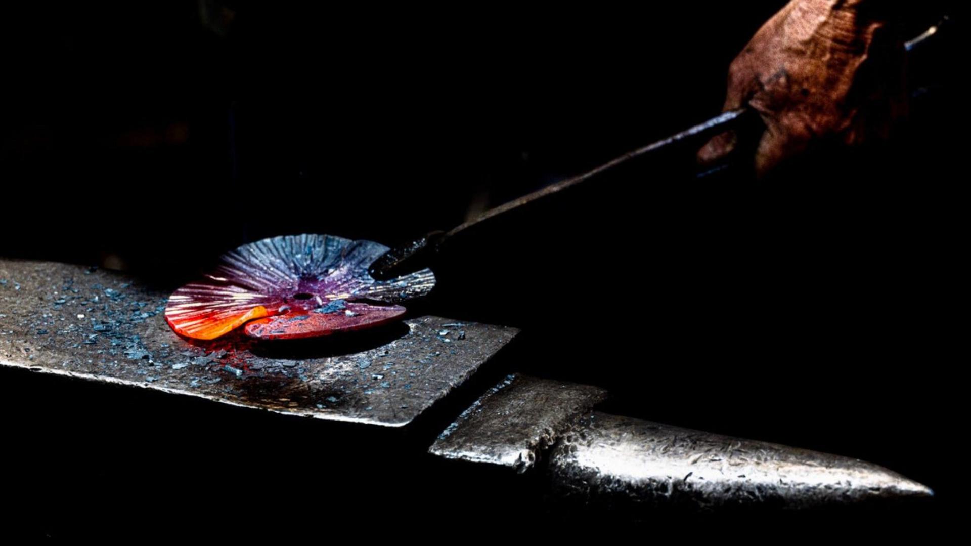 A blacksmith shaping hot glass