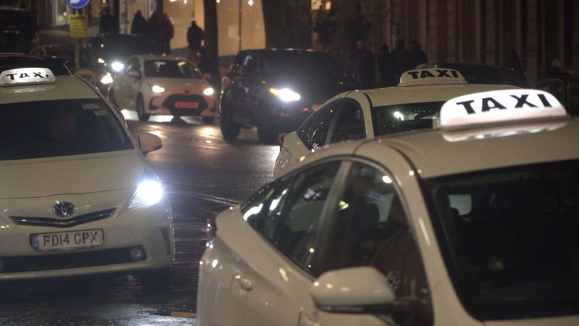 White cars with taxi signs on wait on a taxi rank in Tunbridge Wells.