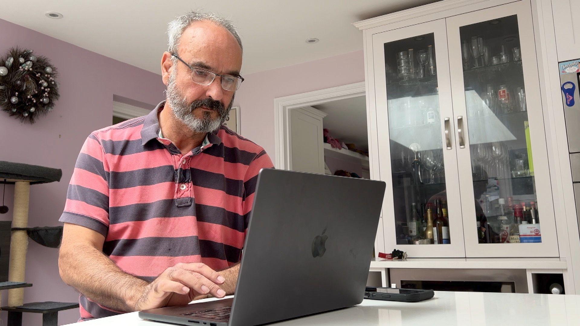 Mark Smith sits at his kitchen table working on his laptop.