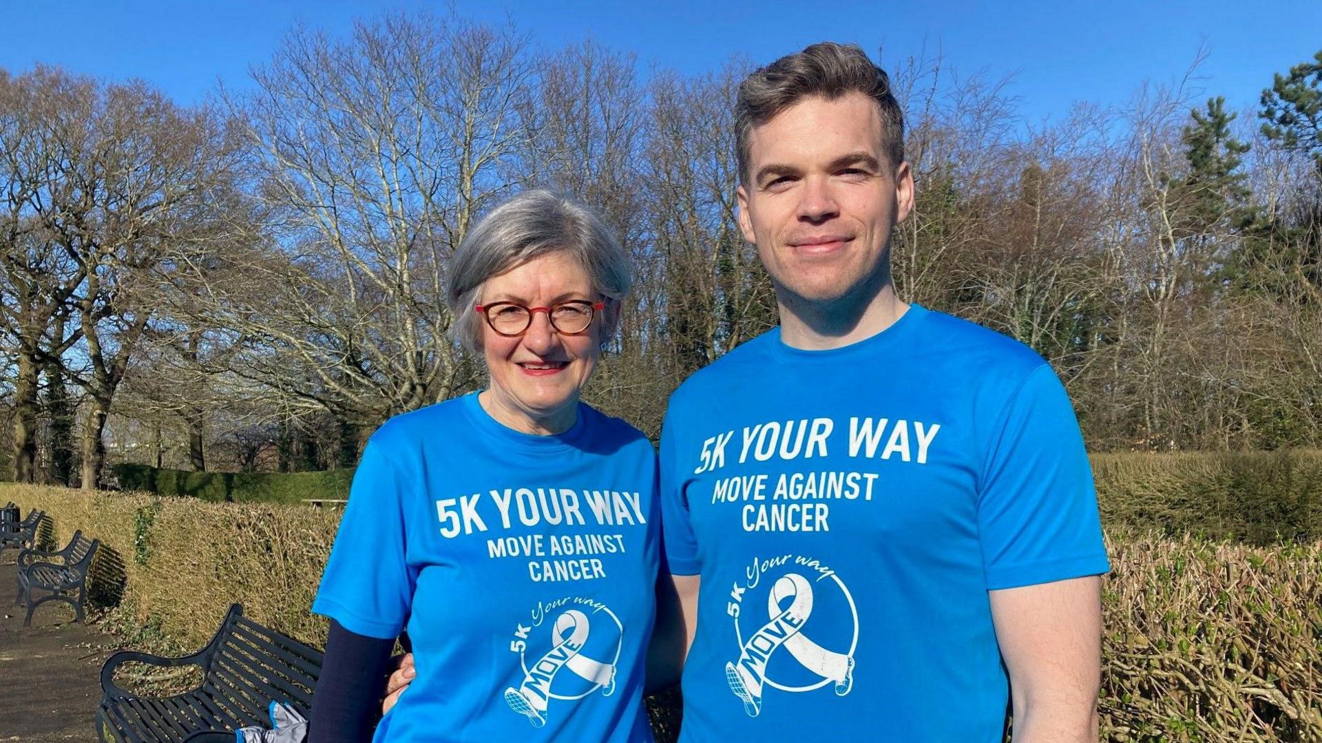 Ann and Kyle pictured wearing blue t-shirts that say '5k your way' 'move against cancer'