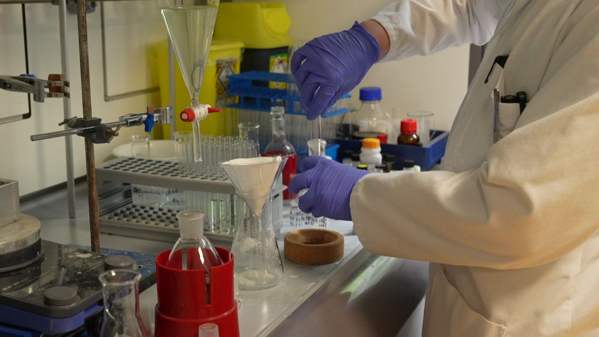 Llun o arbrofion yn cael eu cynnal gan wyddonydd mewn labordy cwmni Draig Therapeutics