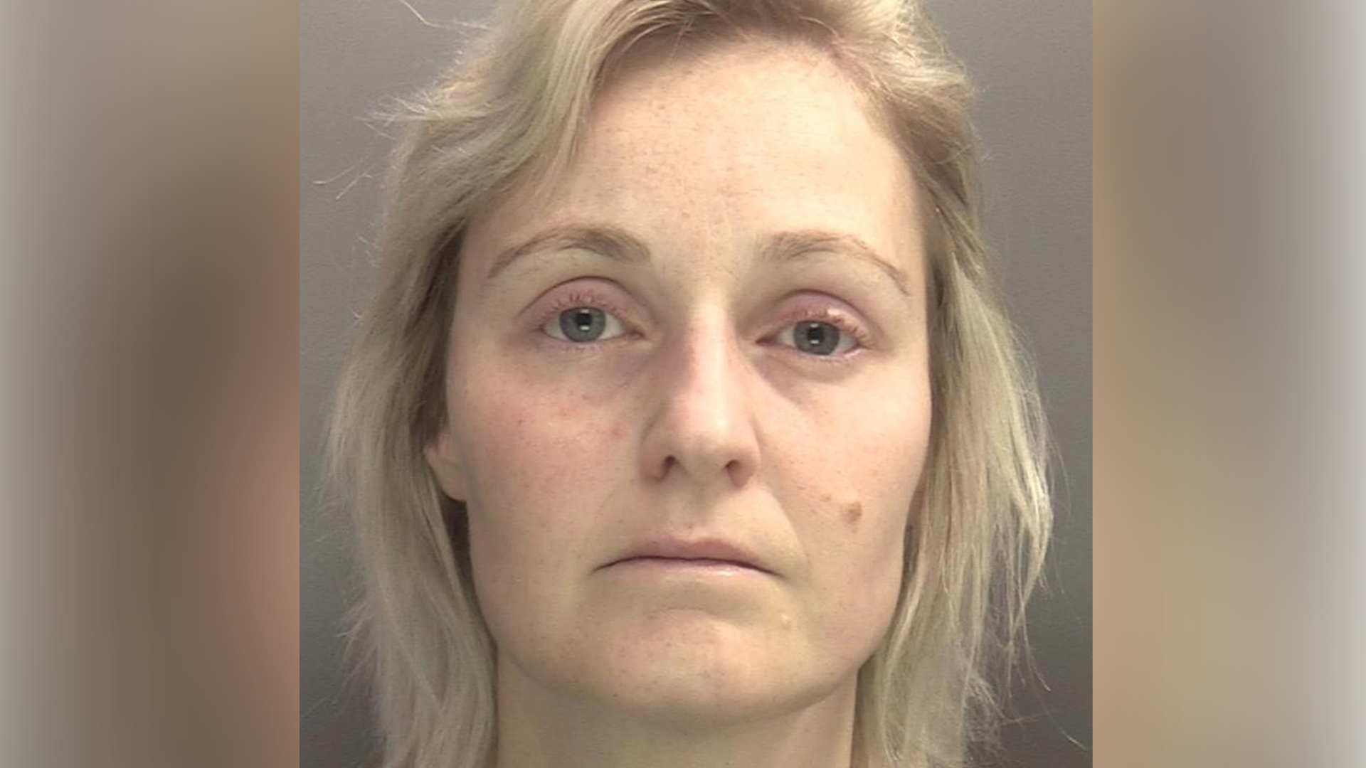 A mug shot of a woman with shoulder length blonde hair