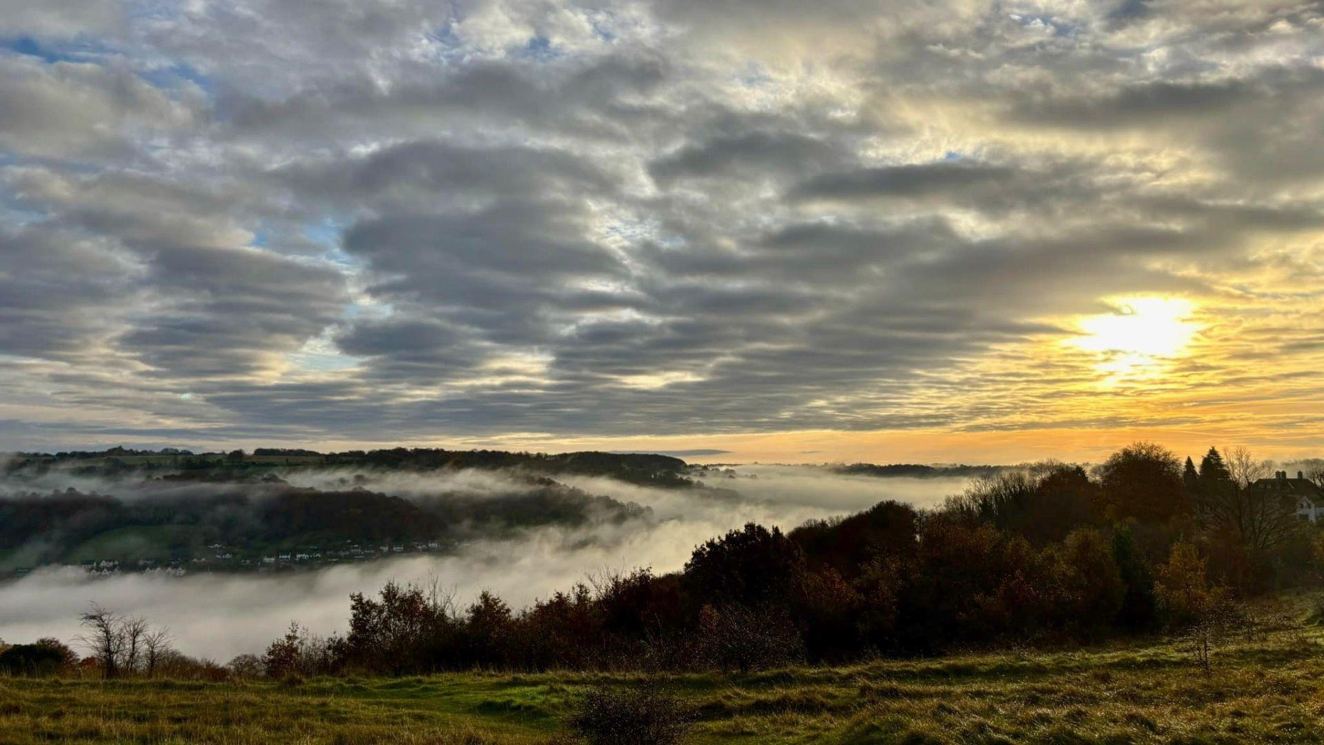 The mist settling across the valley with the sunshine peaking out behind the clouds. 