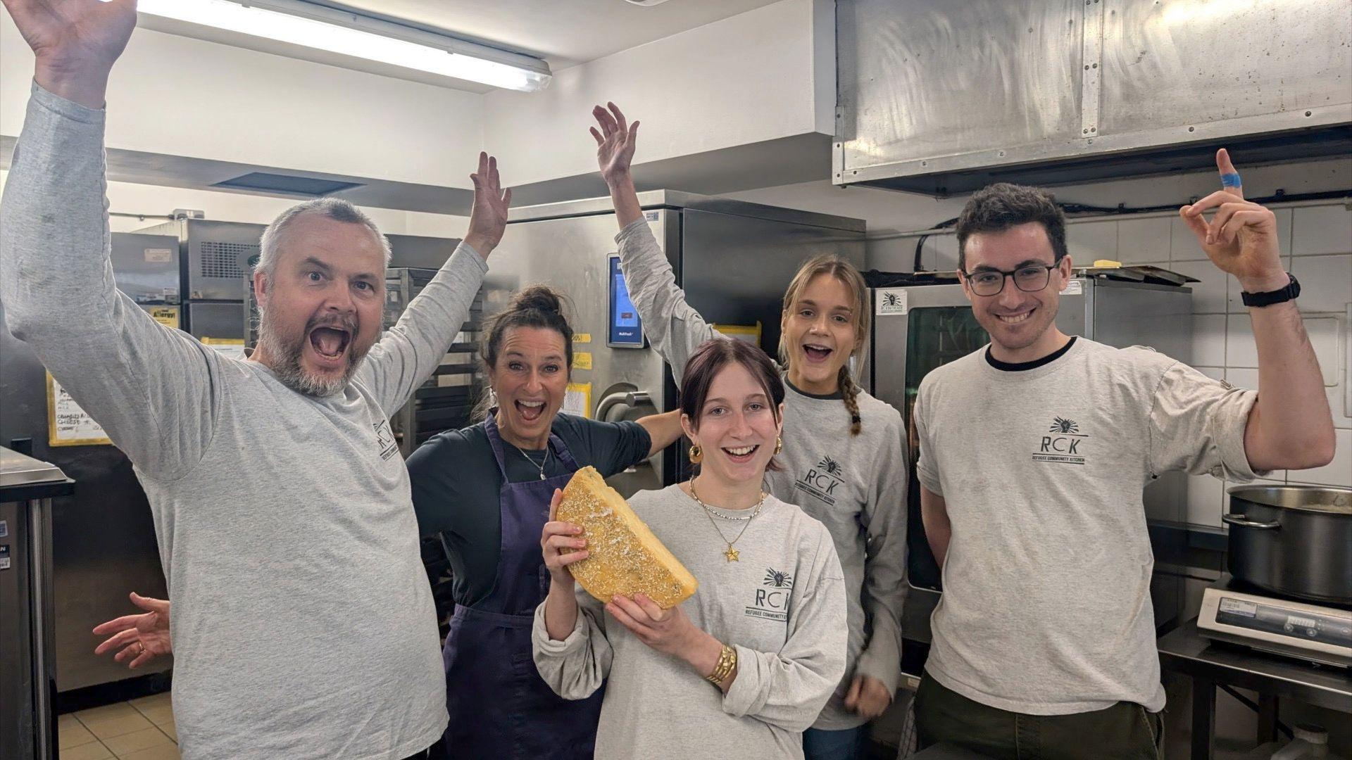 Group of people cheering whilst holding a slice of cheese.