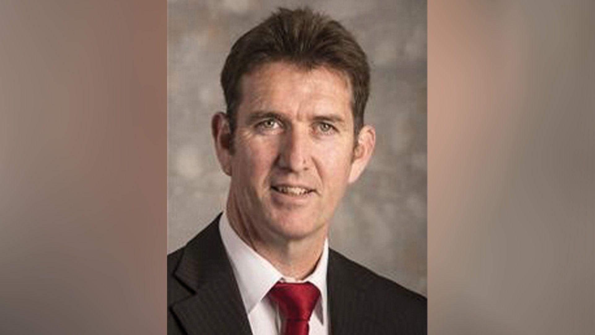 Councillor Eamonn Keogh wearing a black suit, white shirt and red tie. He is smiling at the camera.