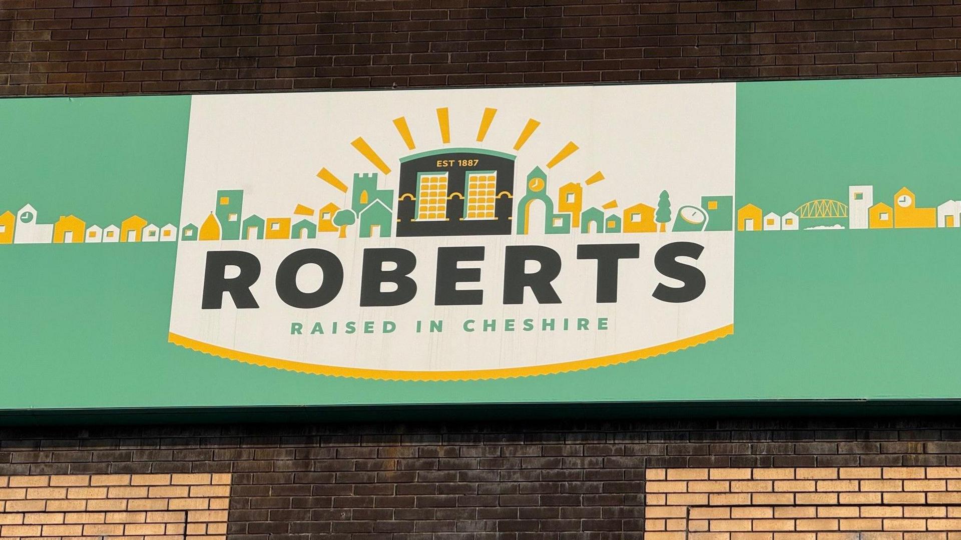Picture of the Roberts signage outside their Northwich factory. The logo which is green and yellow reads 'Roberts - Raised in Cheshire'.