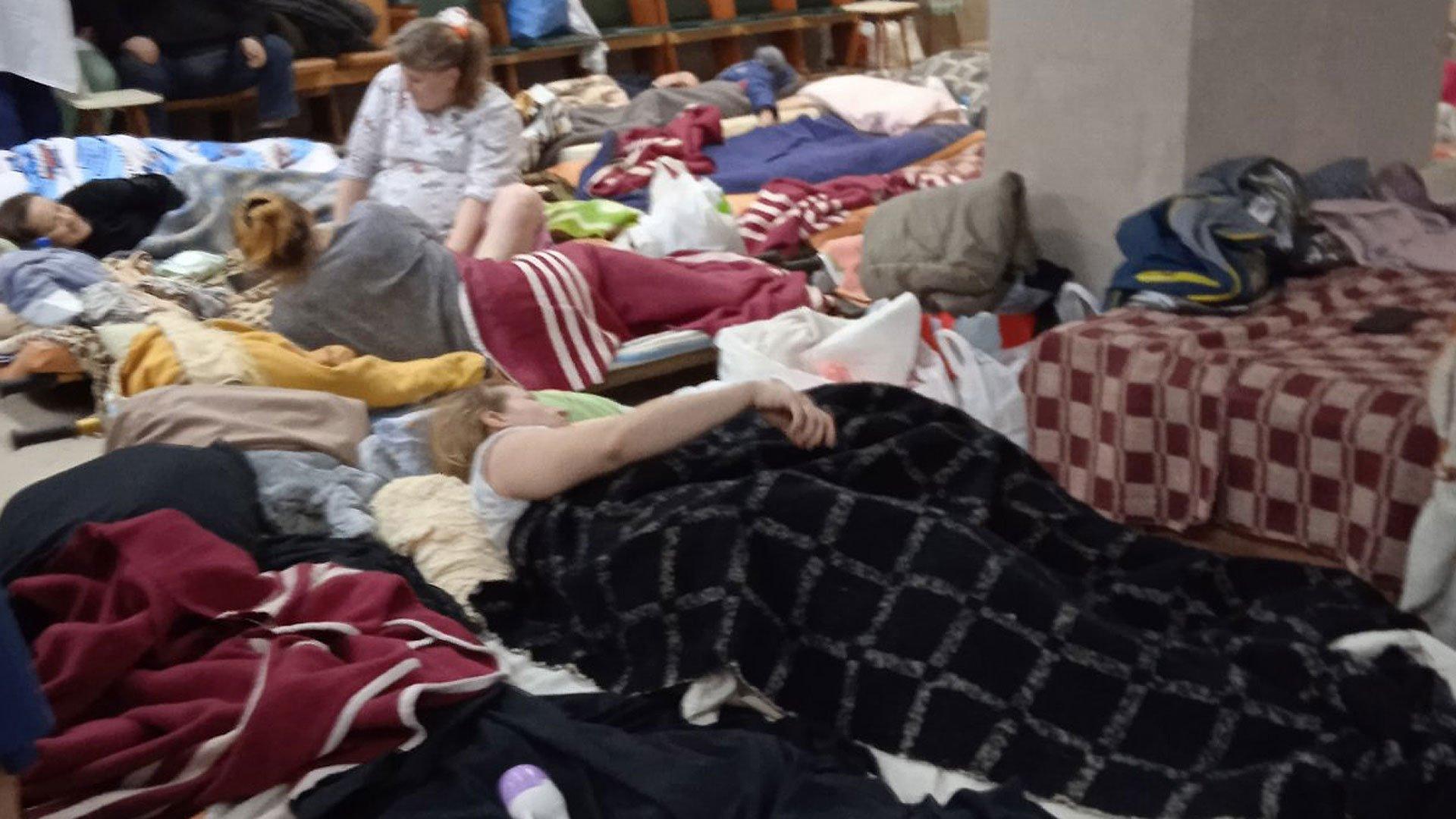 People lying on makeshift beds on the floor of the bomb shelter