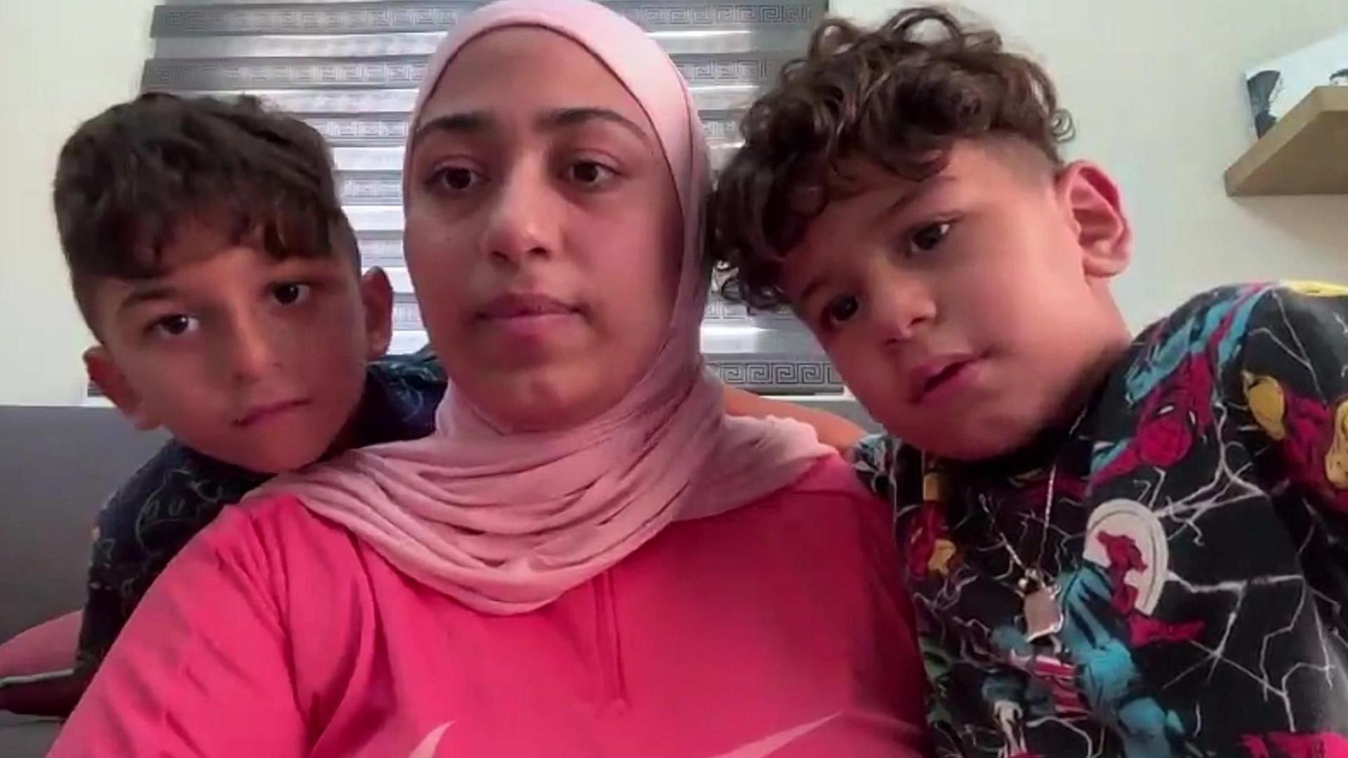 Mahasen al-Dada, wearing a pink top, pictured on a Zoom call. Her young sons are on either side of her.