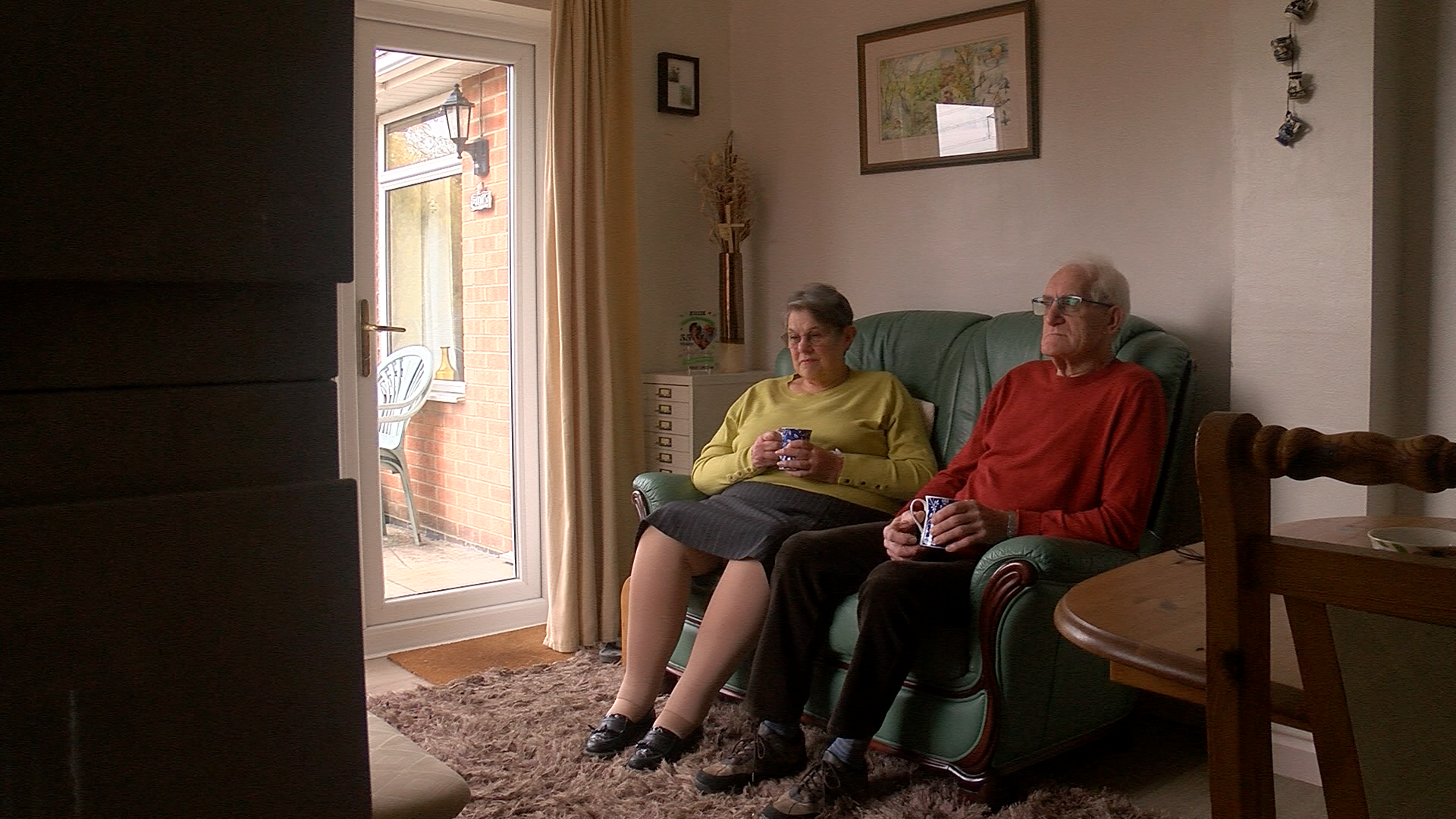 Margaret and David Fee on the sofa with a cup of tea