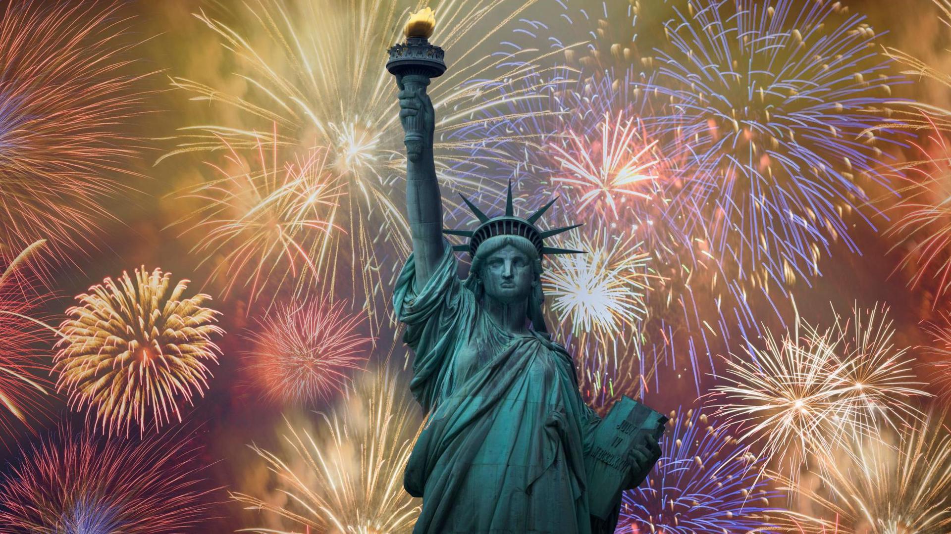 The statue of Liberty in New York with backdrop of fireworks of different filling the sky.