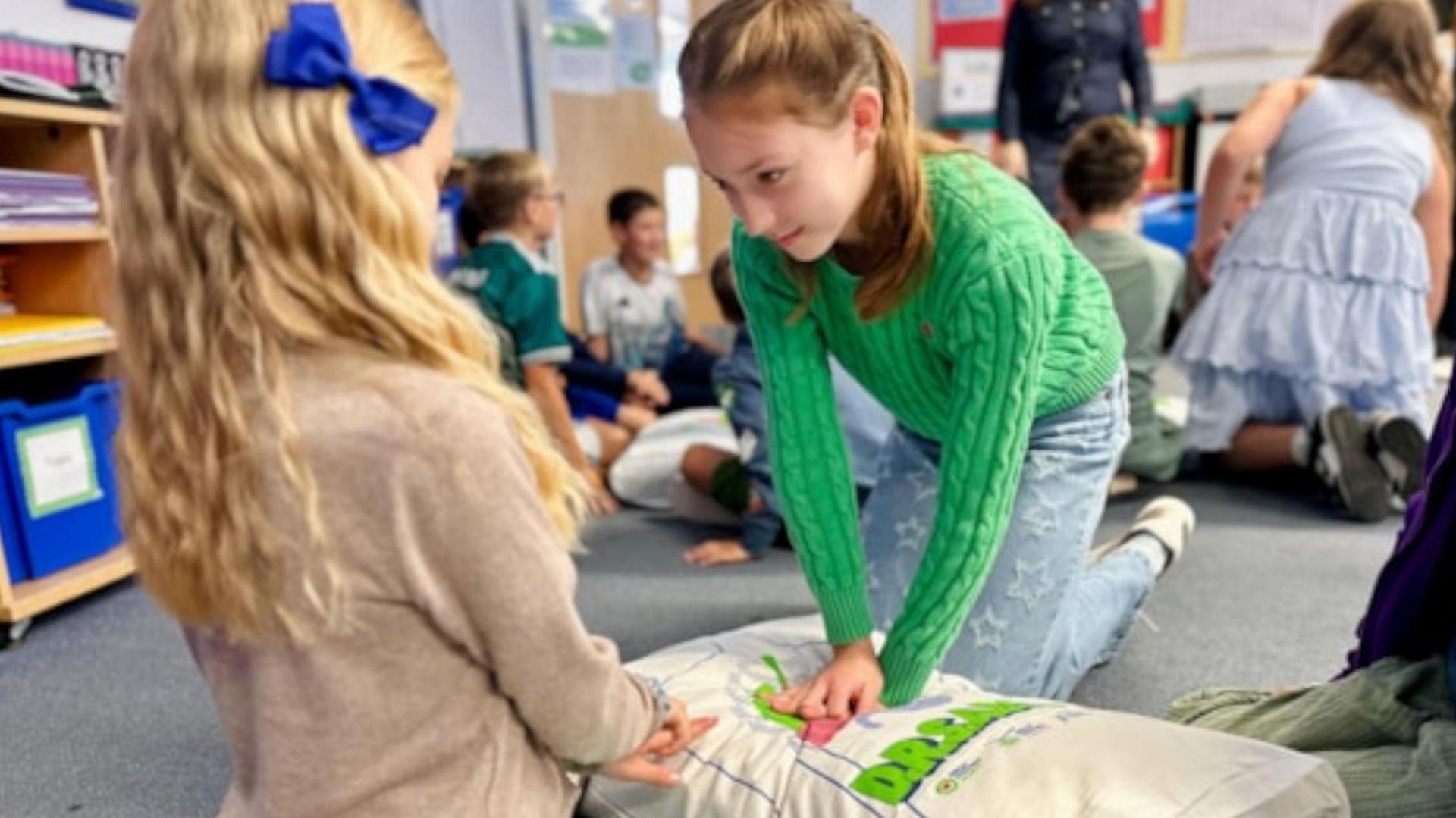A child learning life-saving techniques with another child.