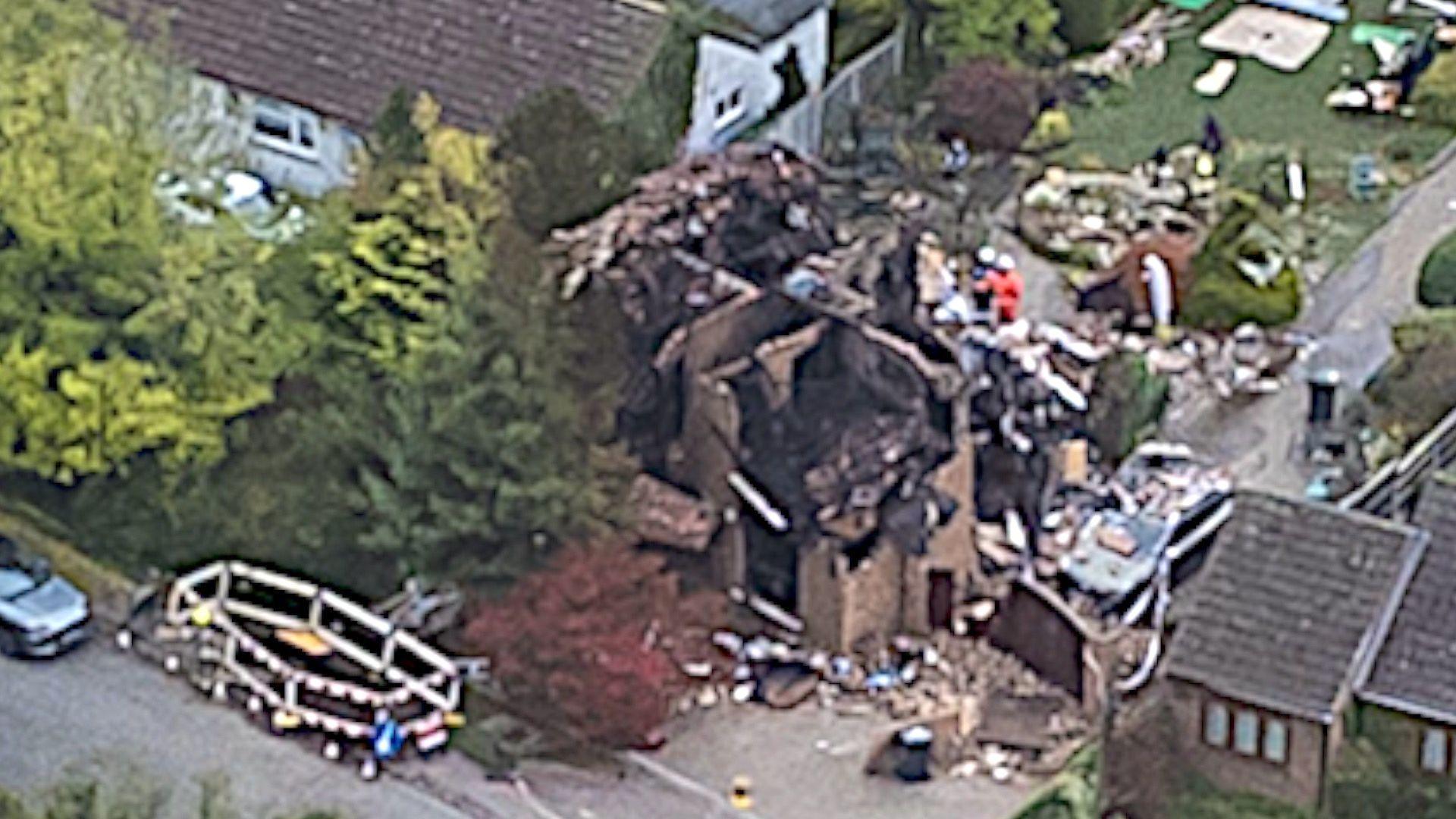 A photo taken by a drone of Cleat Hill after the explosion. Police cars are parked along the street where the destroyed remains of a house can be seen.