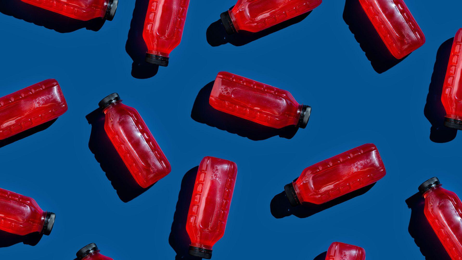 Bottles of cranberry juice dotted around on a dark blue background