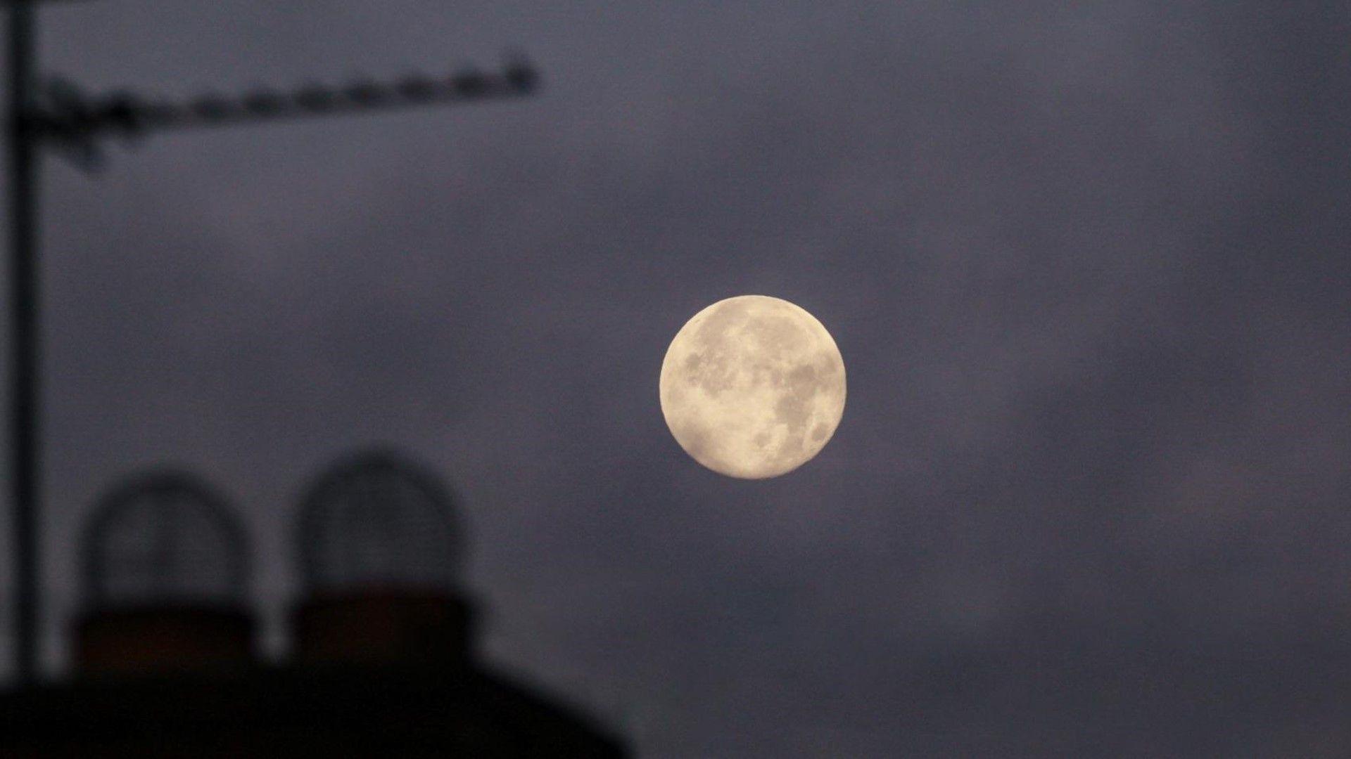 Full moon over rooftops against night sky