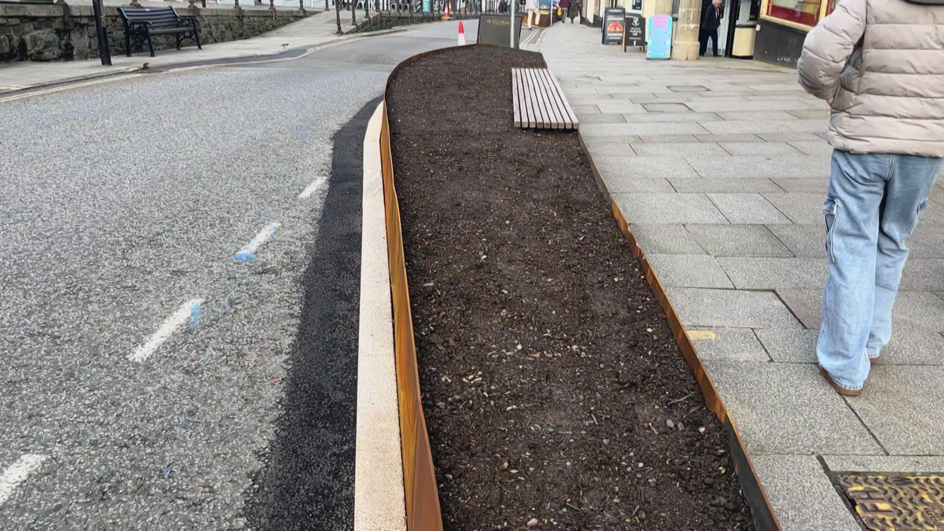 A long planter on the edge of a pavement in Penzance. The exterior is rusty - Inside is bare earth before plants go into it.