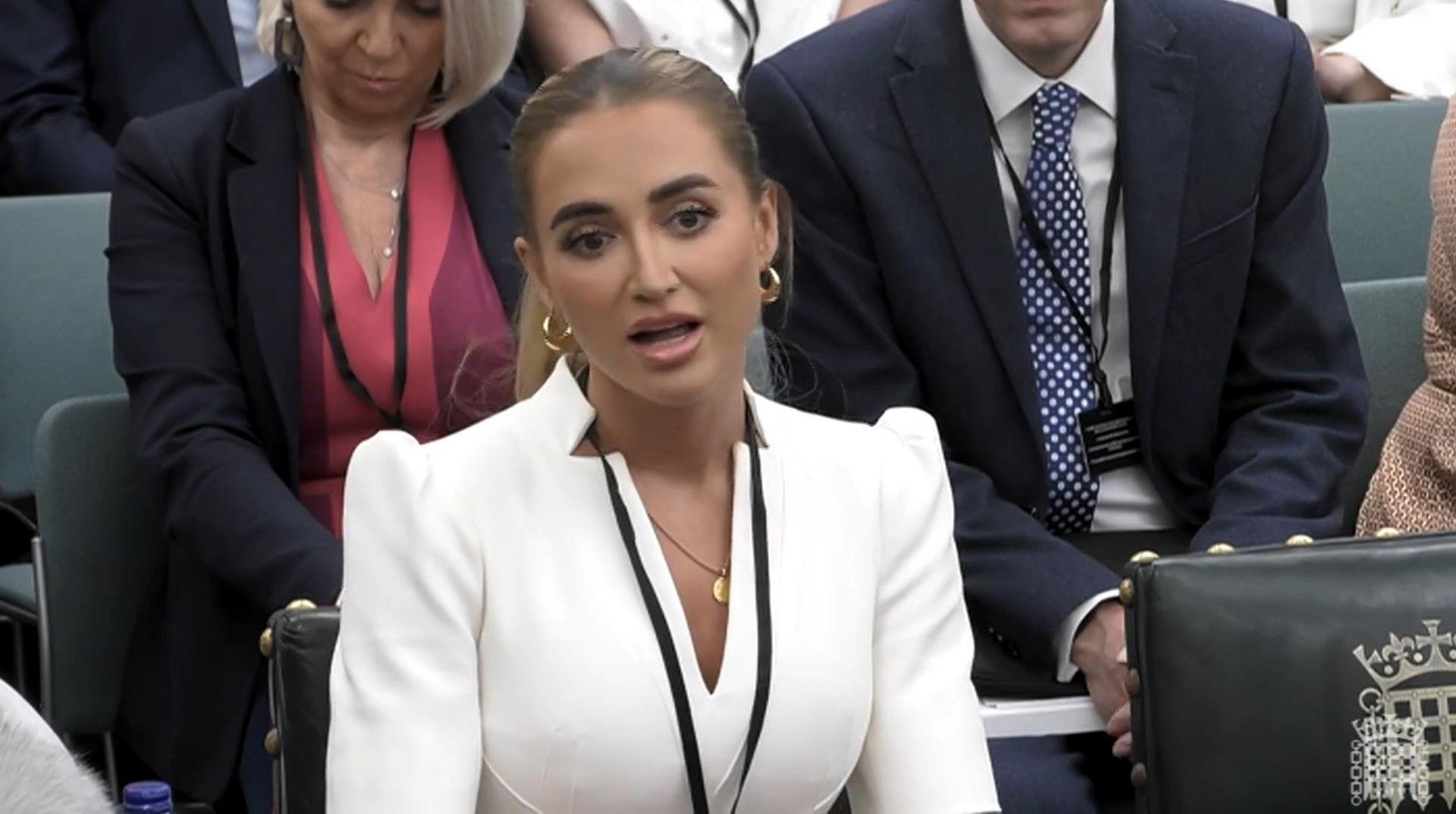 Georgia Harrison wearing a white suit with her hair in a low bun and gold earrings