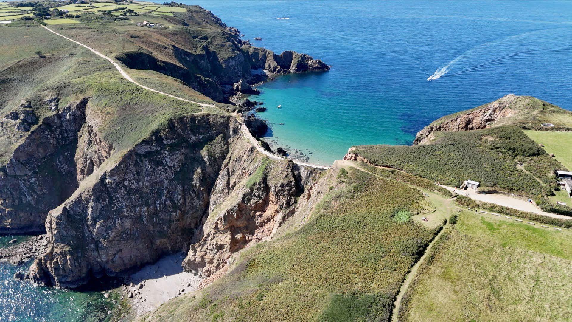 A causeway to Little Sark with blue seas on either side and a path going along the middle.