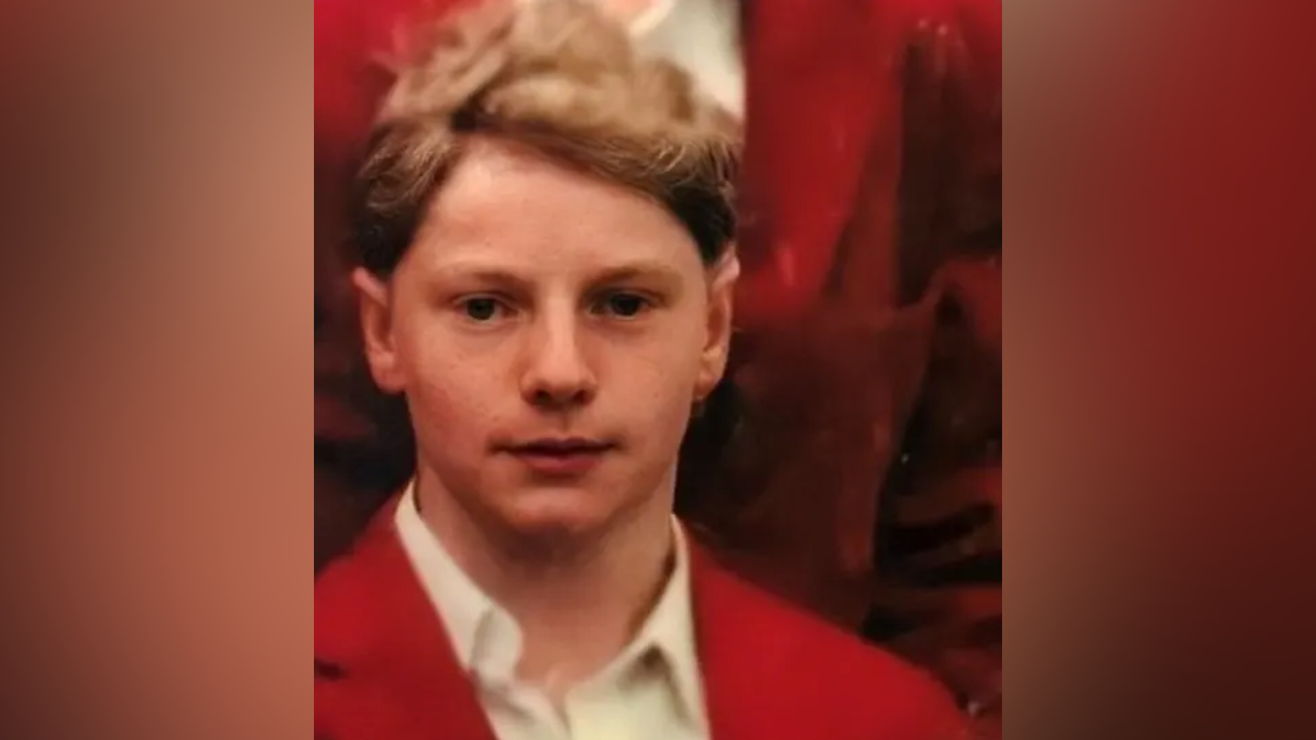 Angus Bell as a pupil at Loretto School in the 1990s wearing a red jacket over a white shirt.