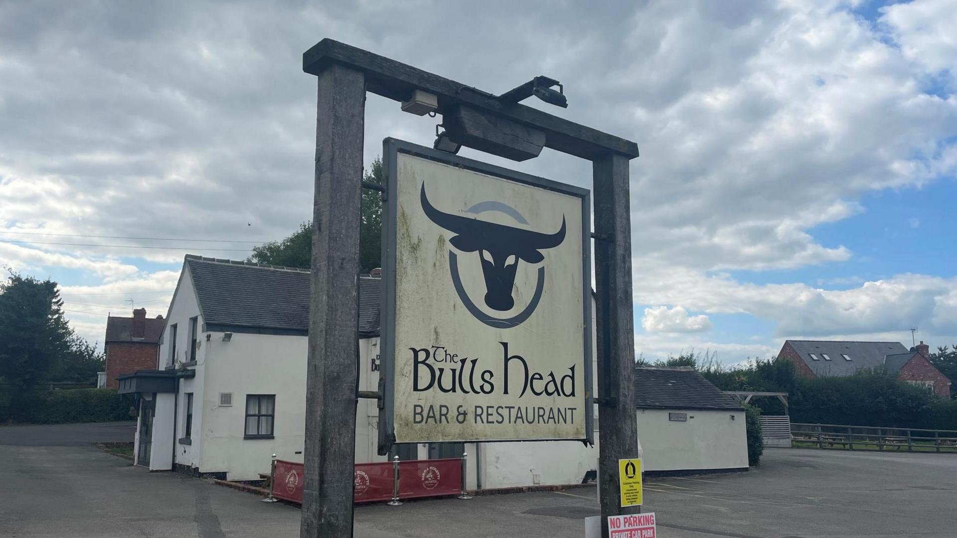 Sign outside Bulls Head, with an empty car park behind it