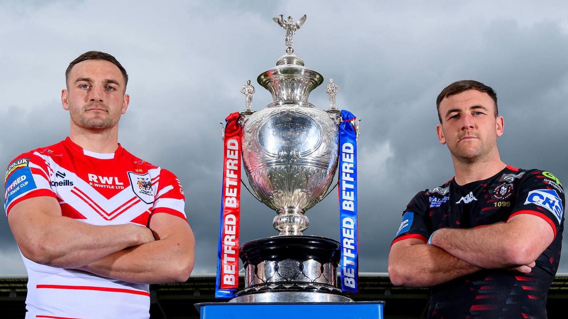 St Helens' Matty Lees and Wigan Warriors' Harry Smith stand alongside the Challenge Cup trophy