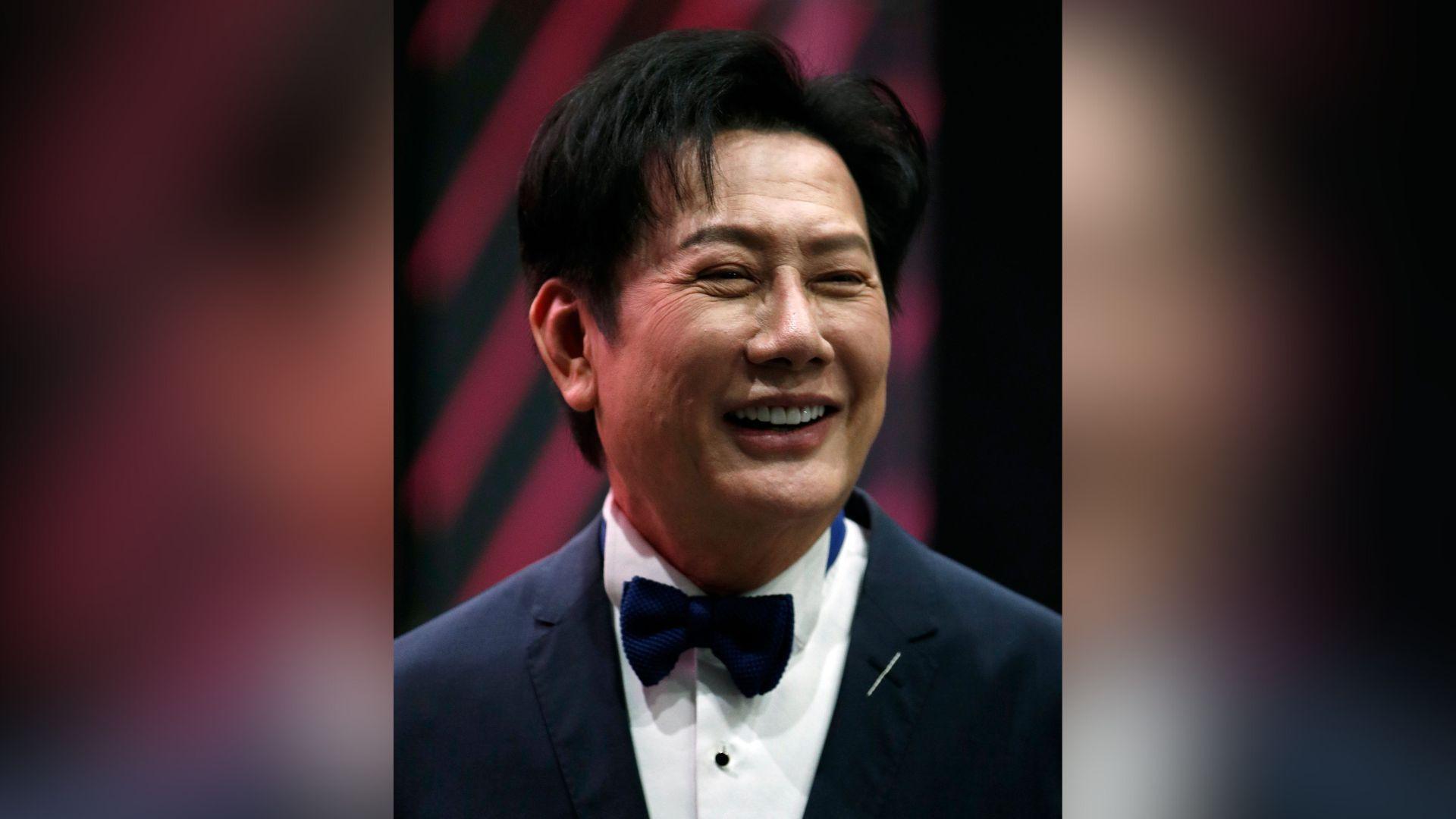 Nawat Itsaragrisil smiles in a tuxedo on the red carpet