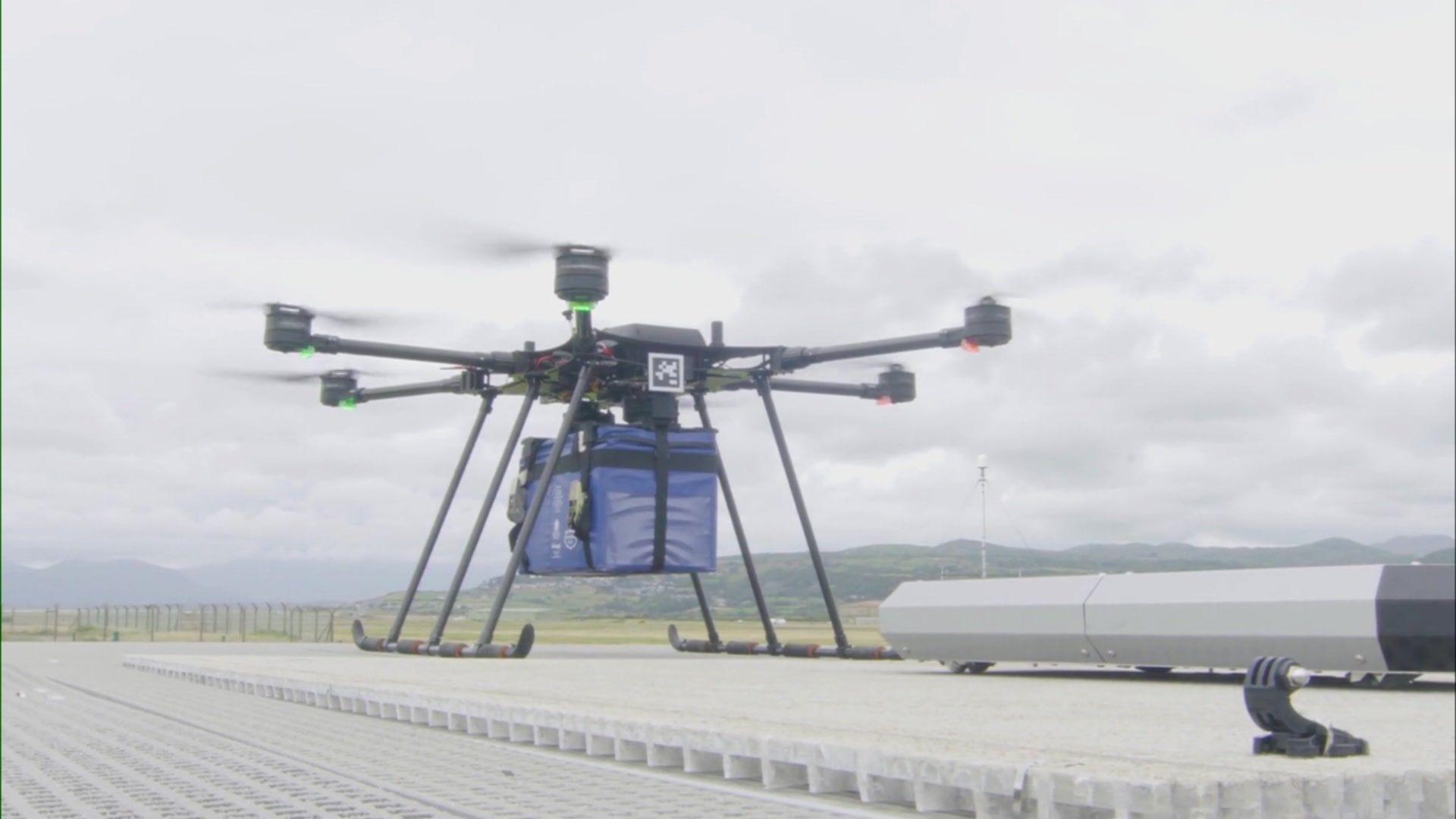 An image of a drone with its propellers whirling around as it sits on a roof of a container