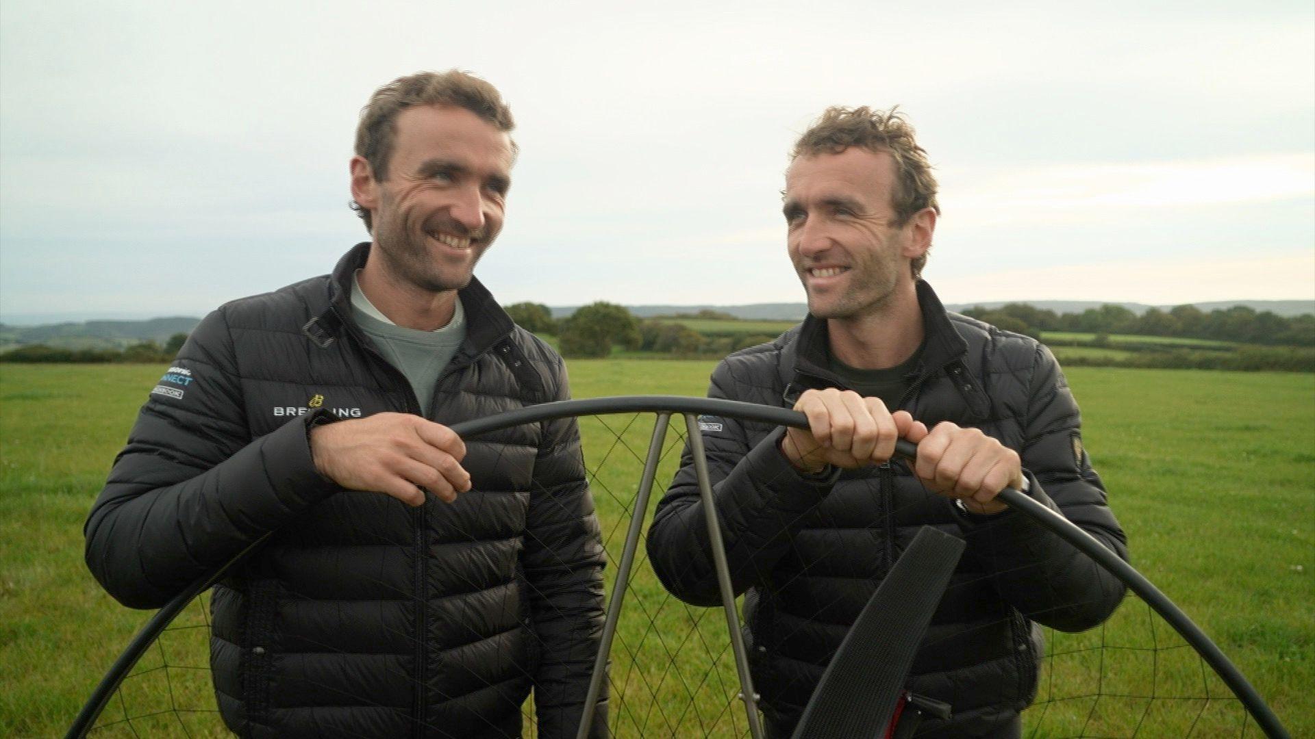 The Turner Twins holding the upright propeller of the electric paramotor. They are both smiling.