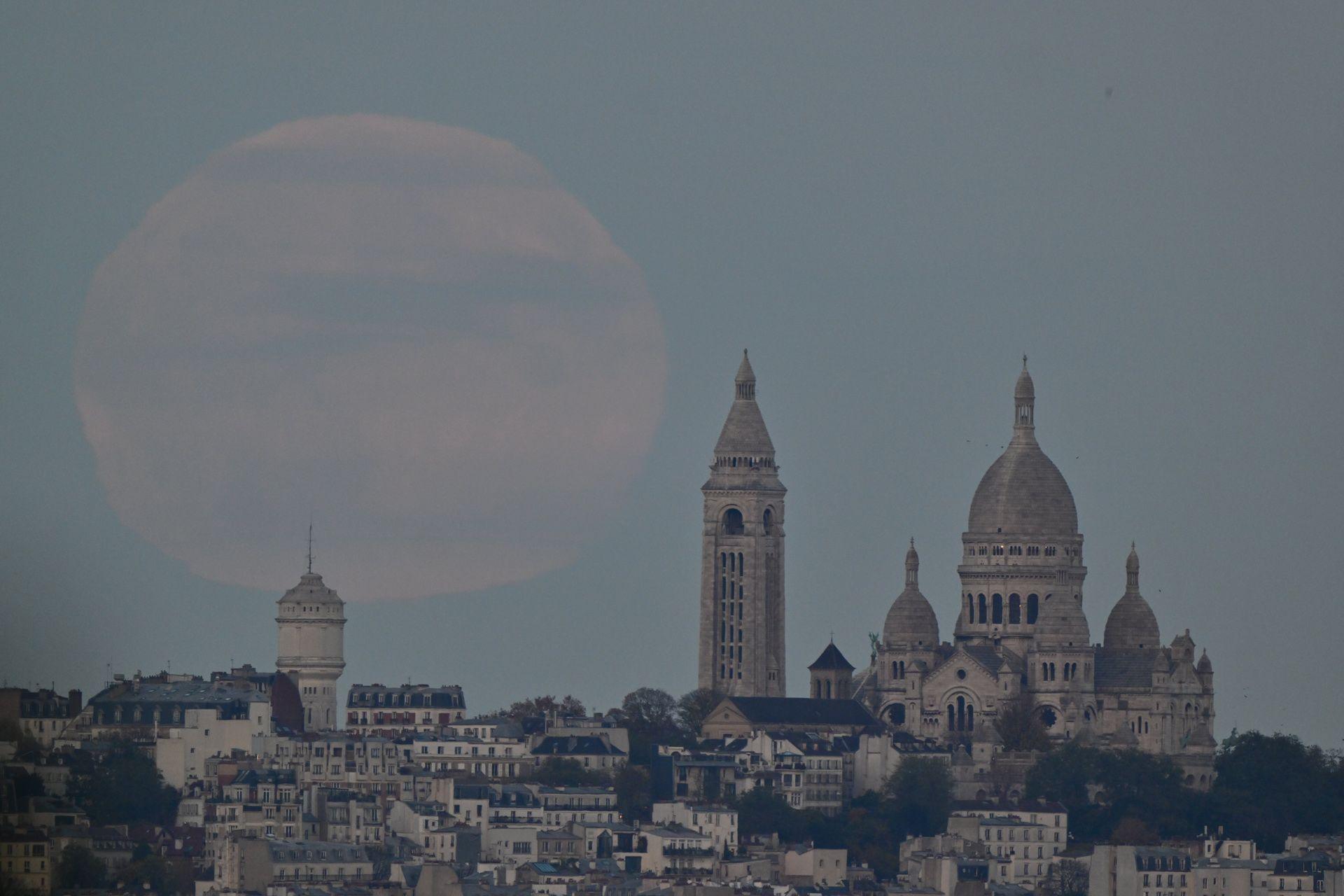 The Moon appears large with clouds in front of it against the Paris skyline as night begins to fall on Wednesday.