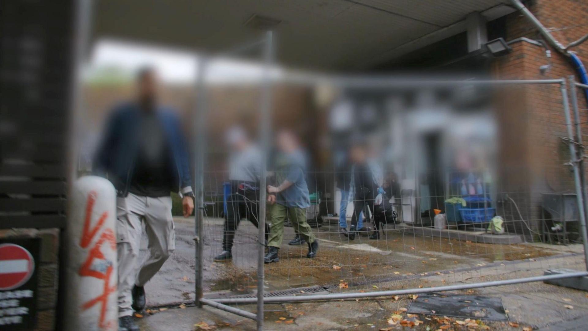 Illegal workers - whose faces are blurred - being led out of the forecourt of car wash in south London