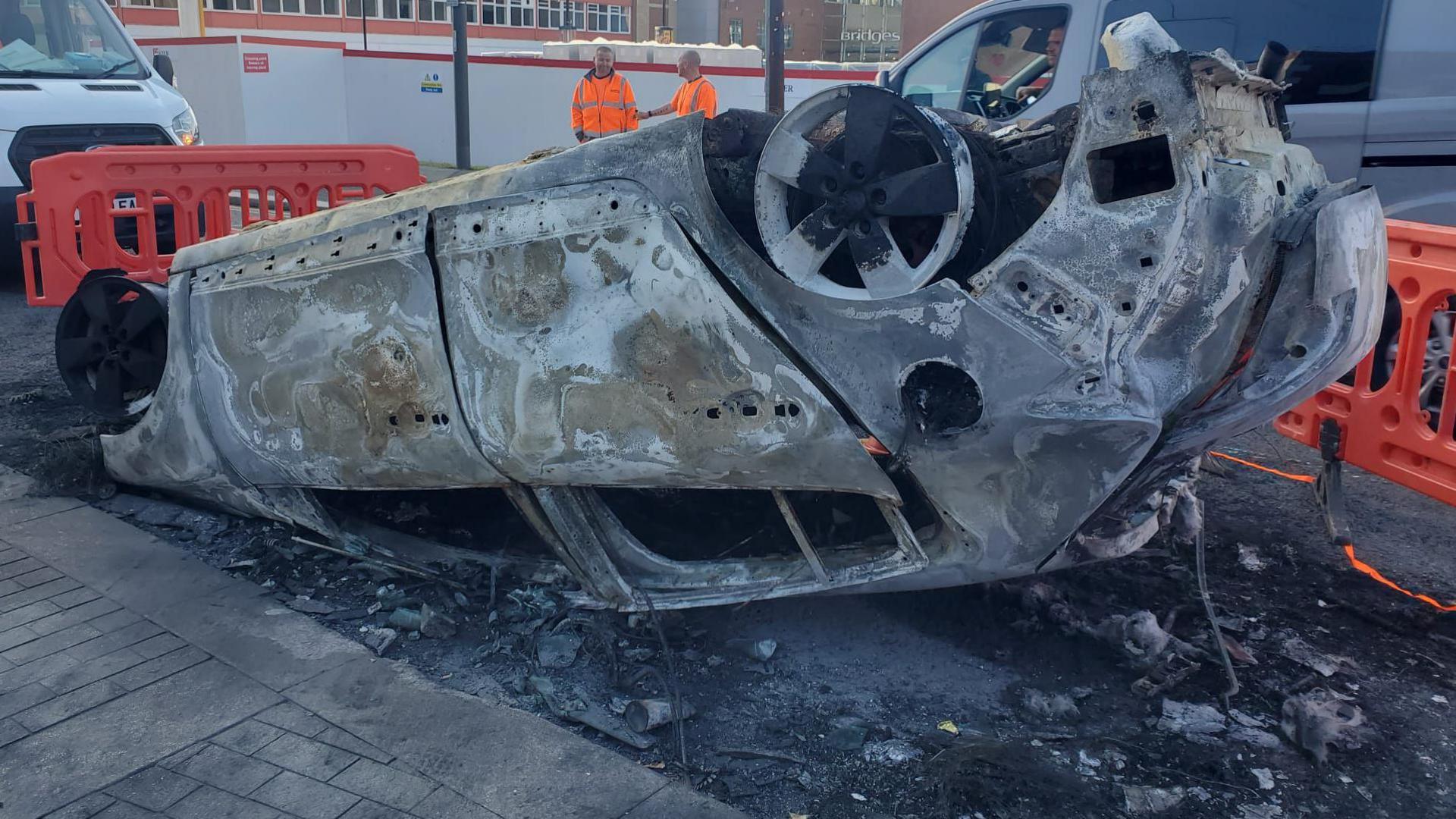 There is a car lying on its roof, completely burned out after being set alight during the riots last summer.